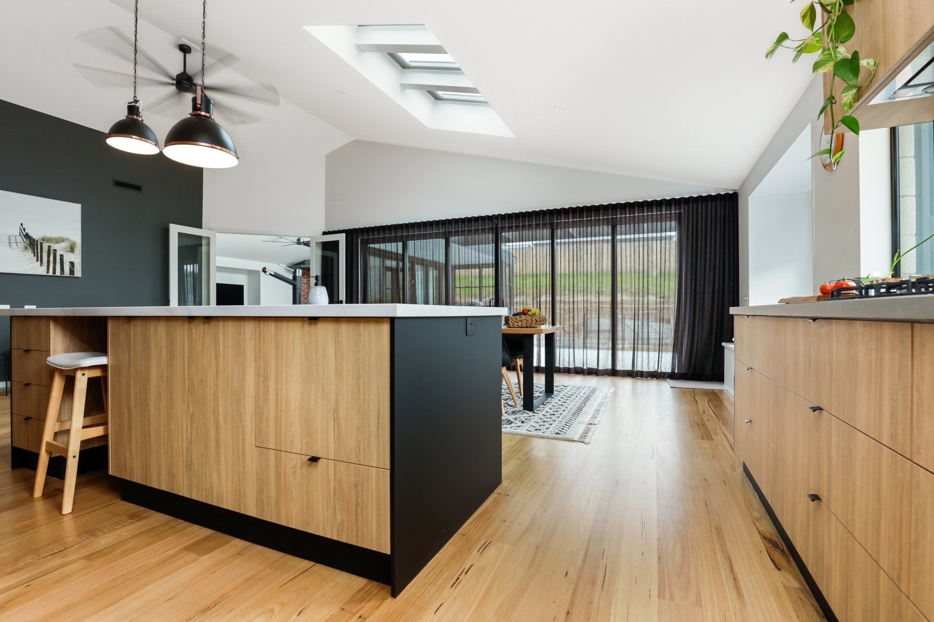 A kitchen with wooden cabinets and stools and a large island in the middle.