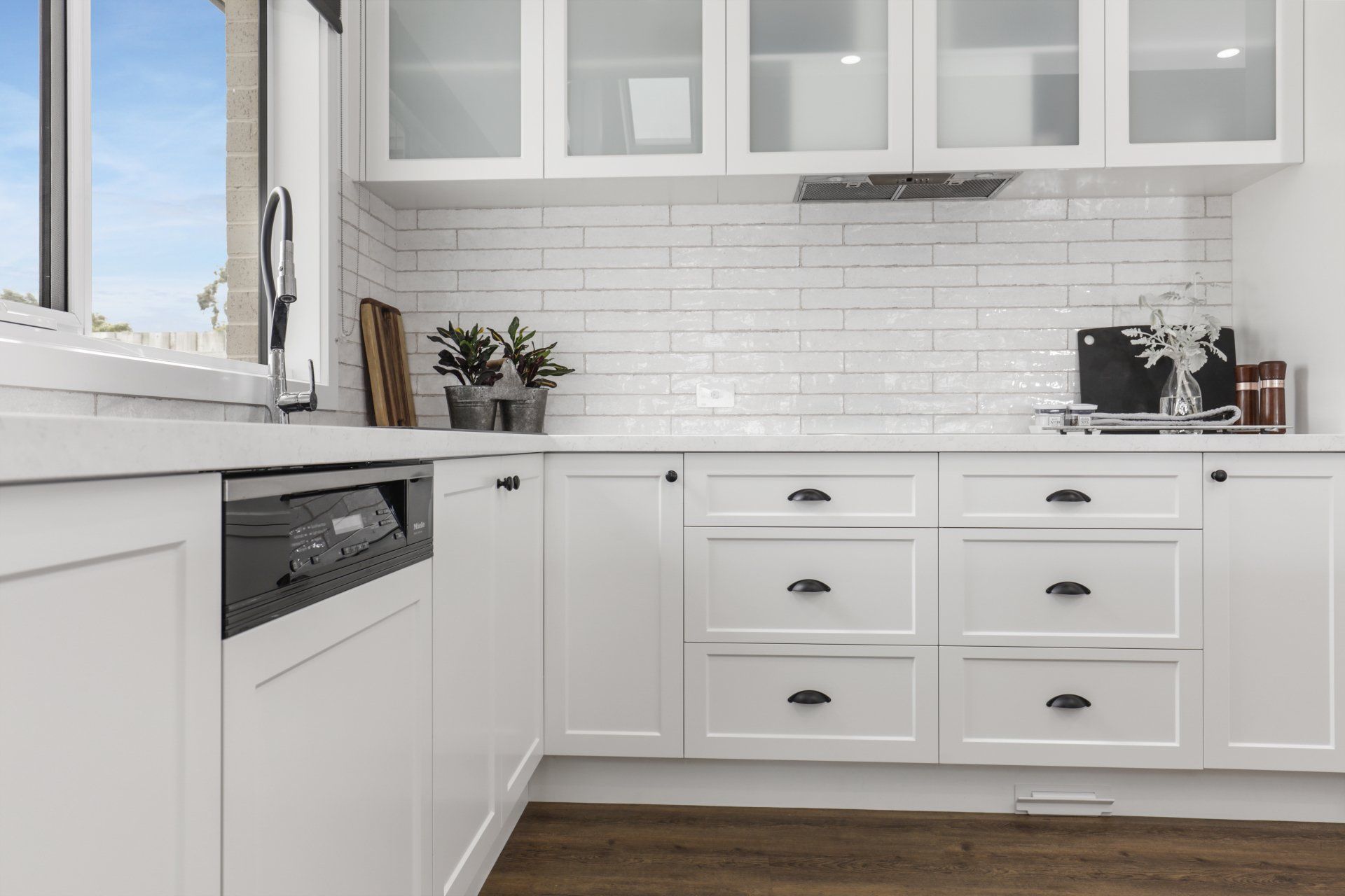 A kitchen with white cabinets and a black dishwasher.