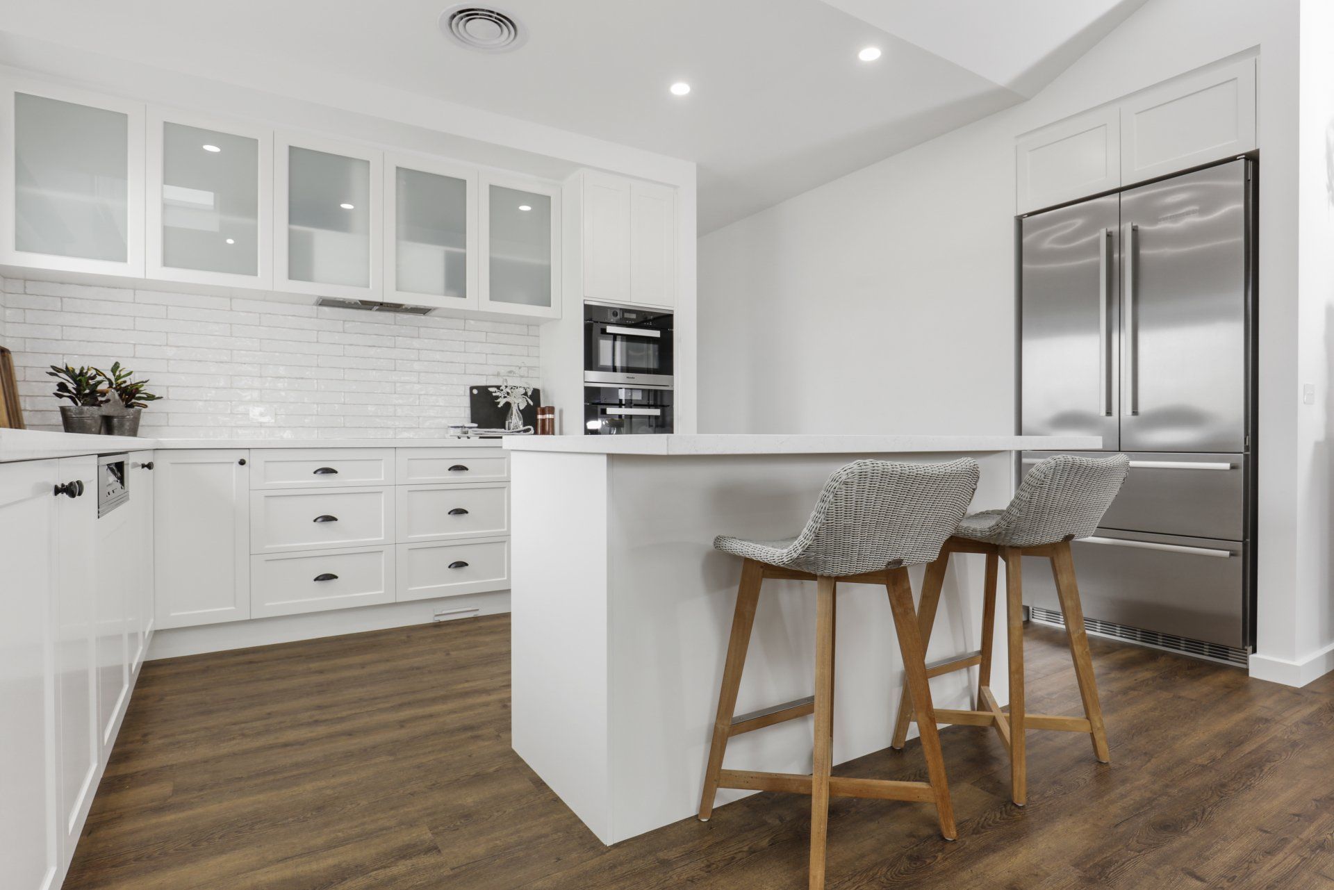 A kitchen with white cabinets , stainless steel appliances , and wooden floors.