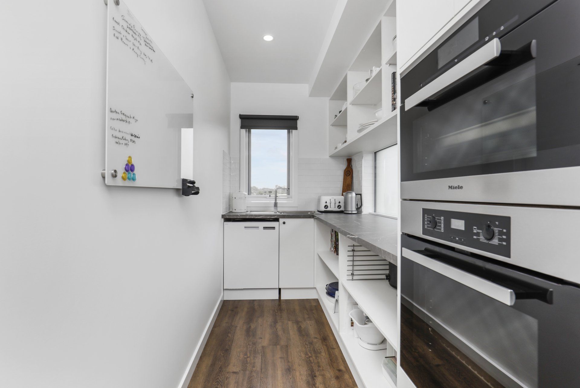 A kitchen with stainless steel appliances and a white board on the wall.
