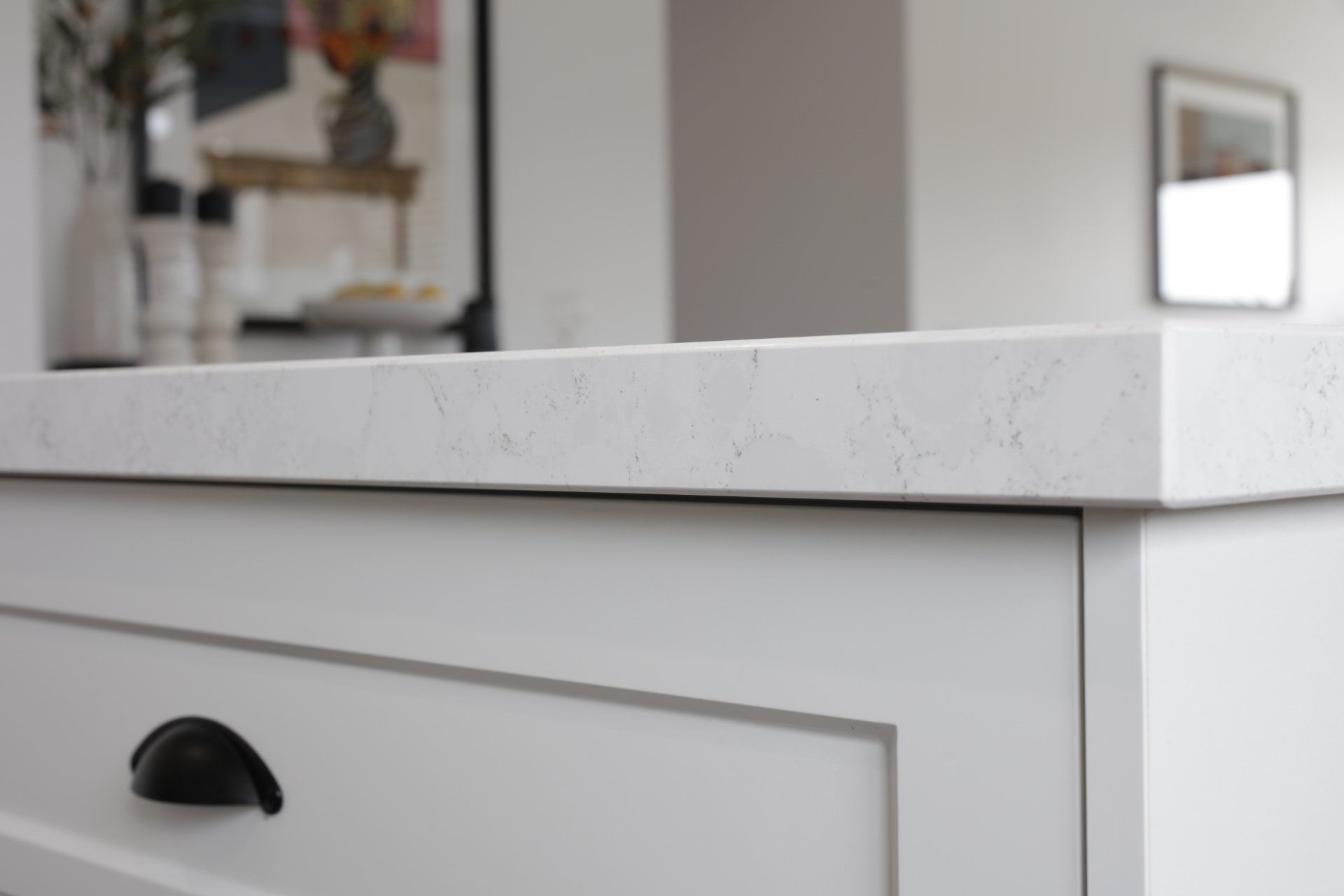 A white cabinet with a black handle and a white counter top.