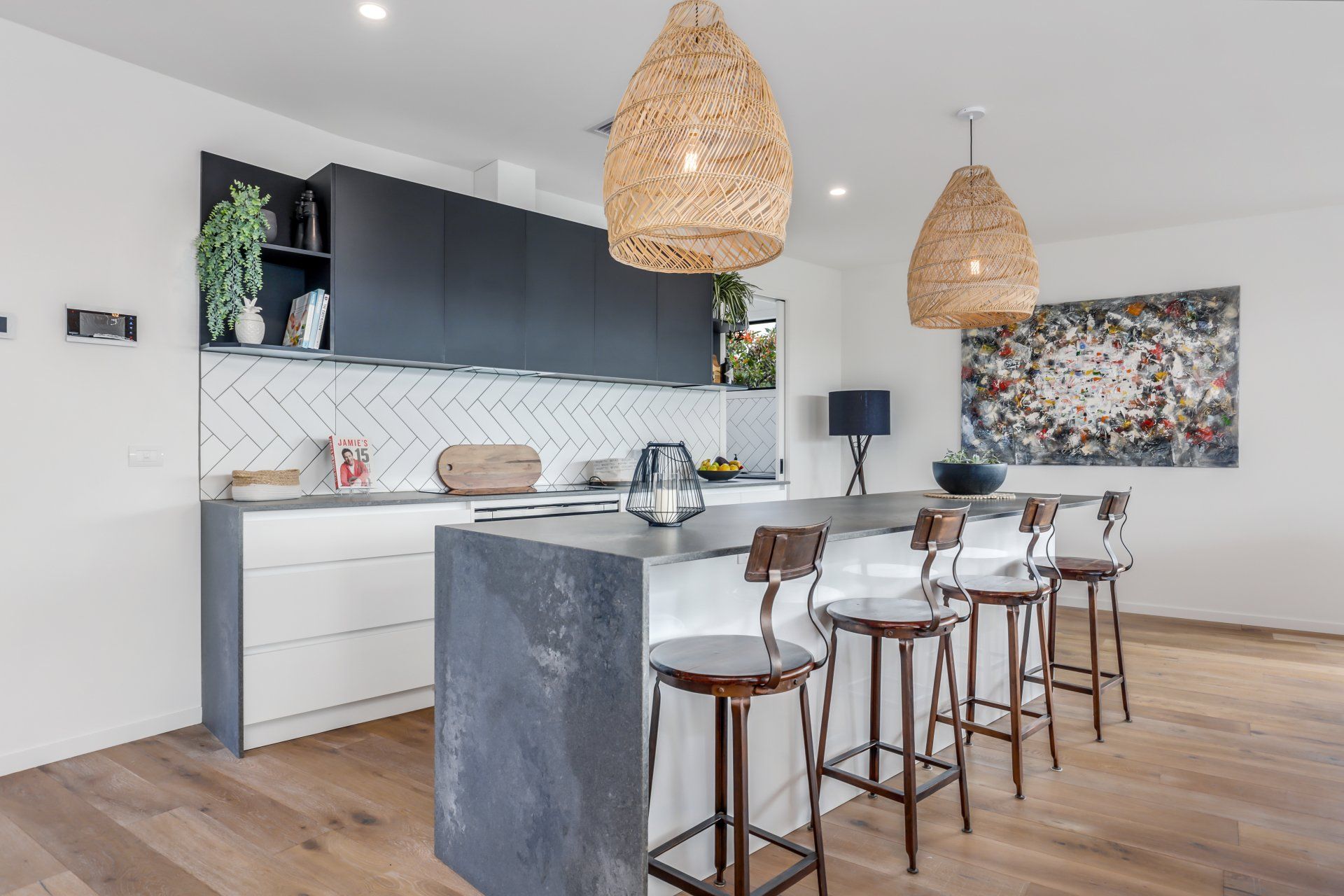 A kitchen with a large island and stools and a painting on the wall.