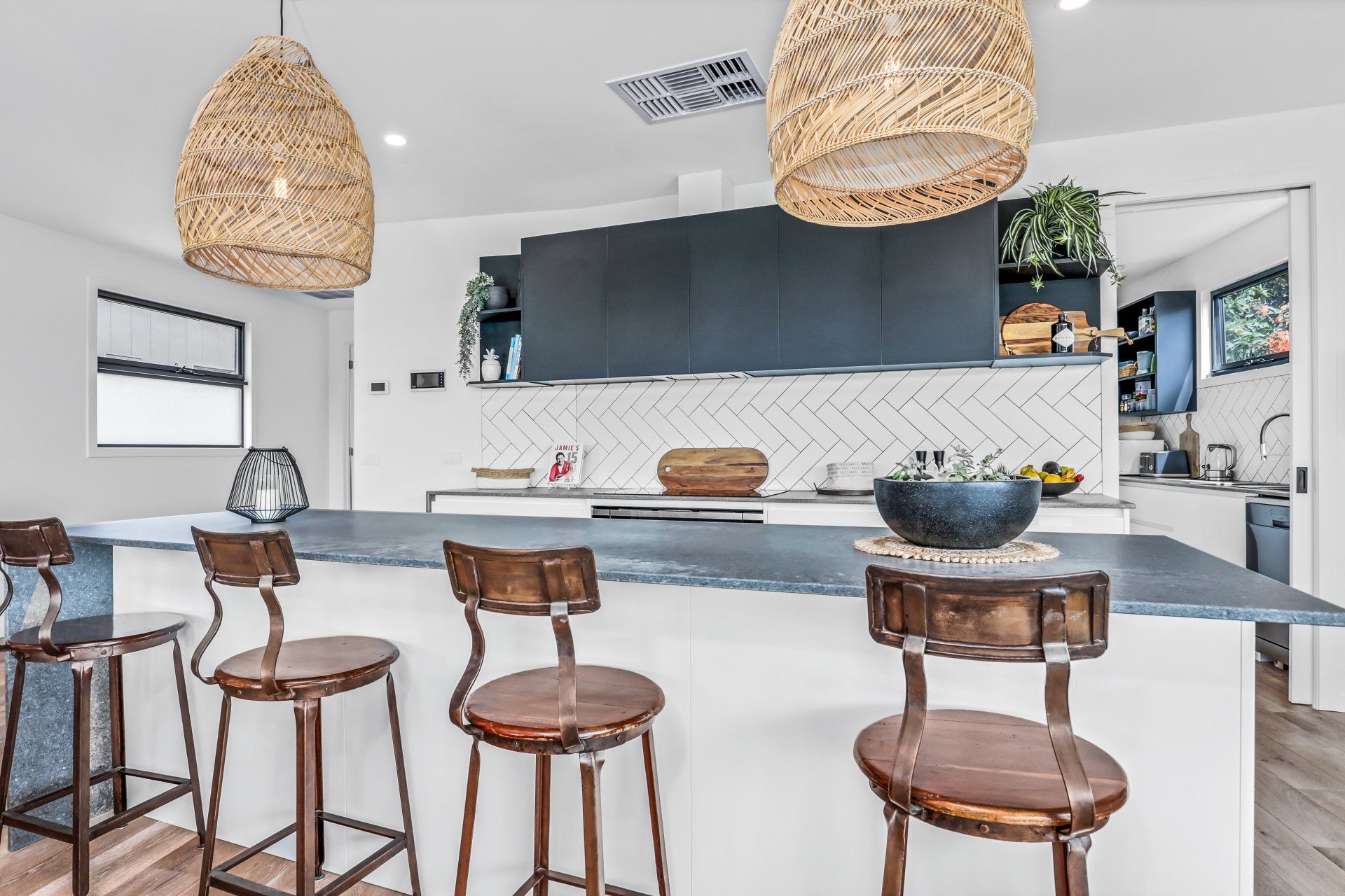 A kitchen with a large island and stools and a bowl on the counter.
