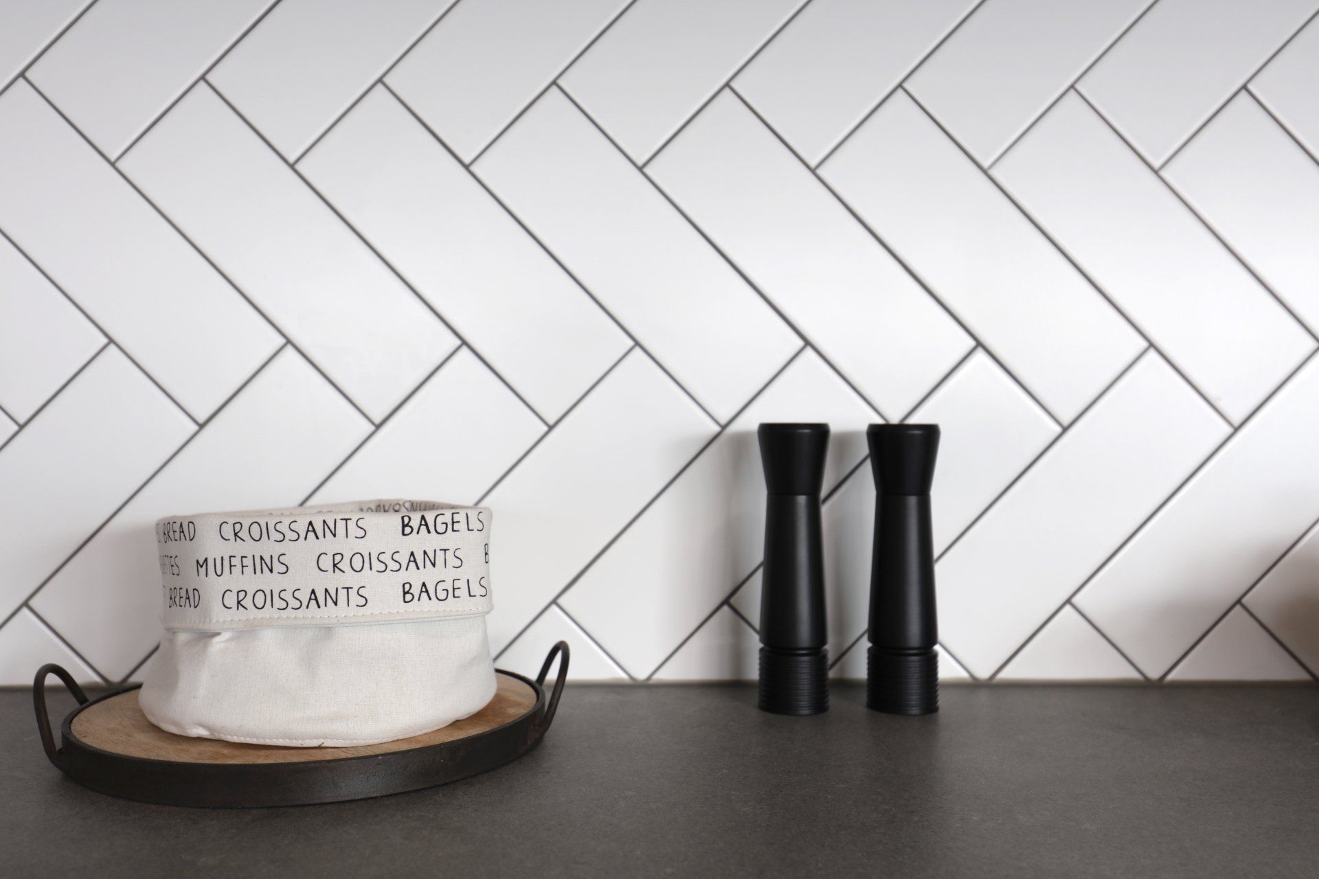 Two black salt and pepper shakers are sitting on a counter next to a bag of croissants