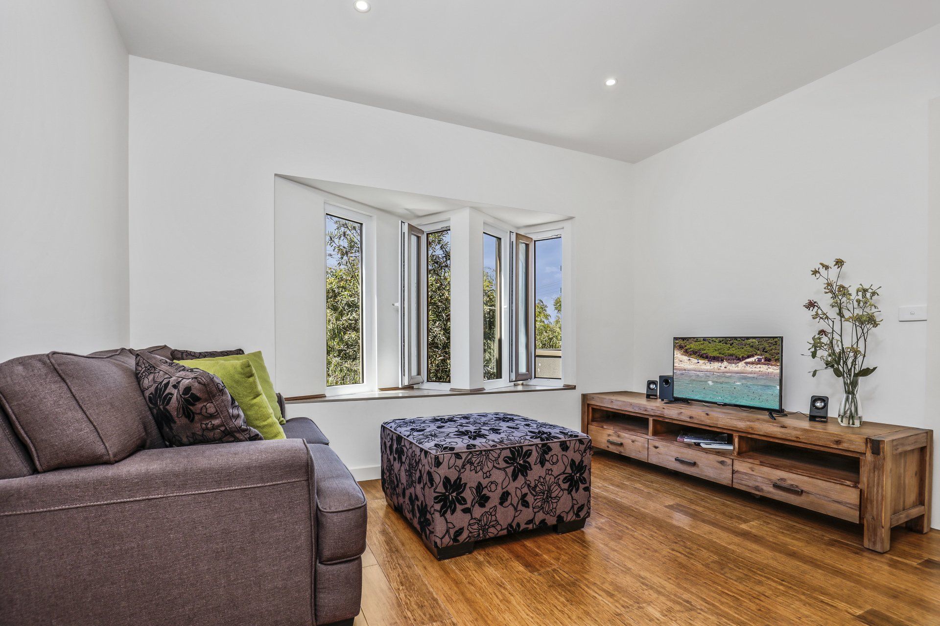 A living room with a couch , ottoman , and television.
