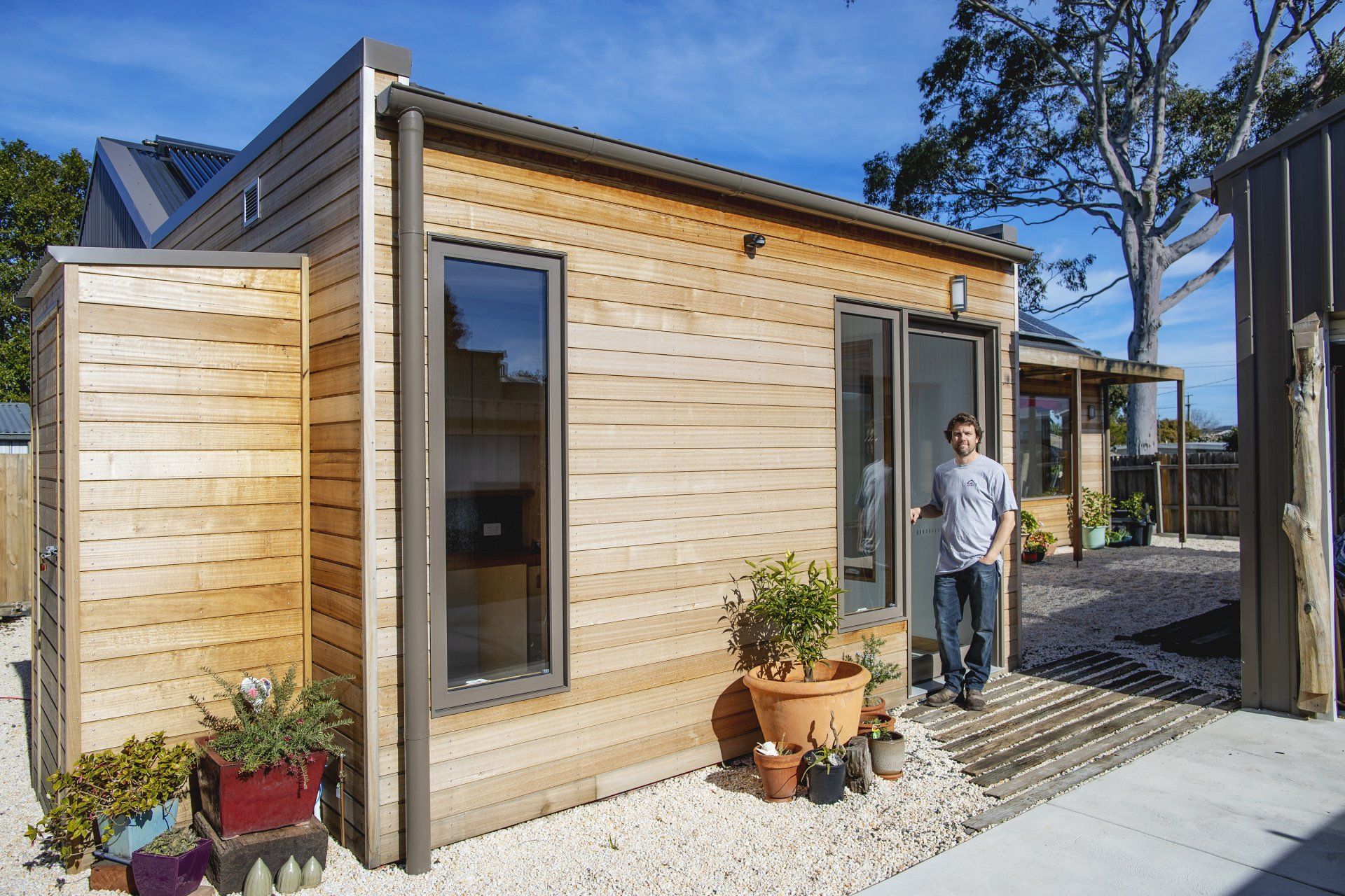 A man is standing in front of a small wooden house