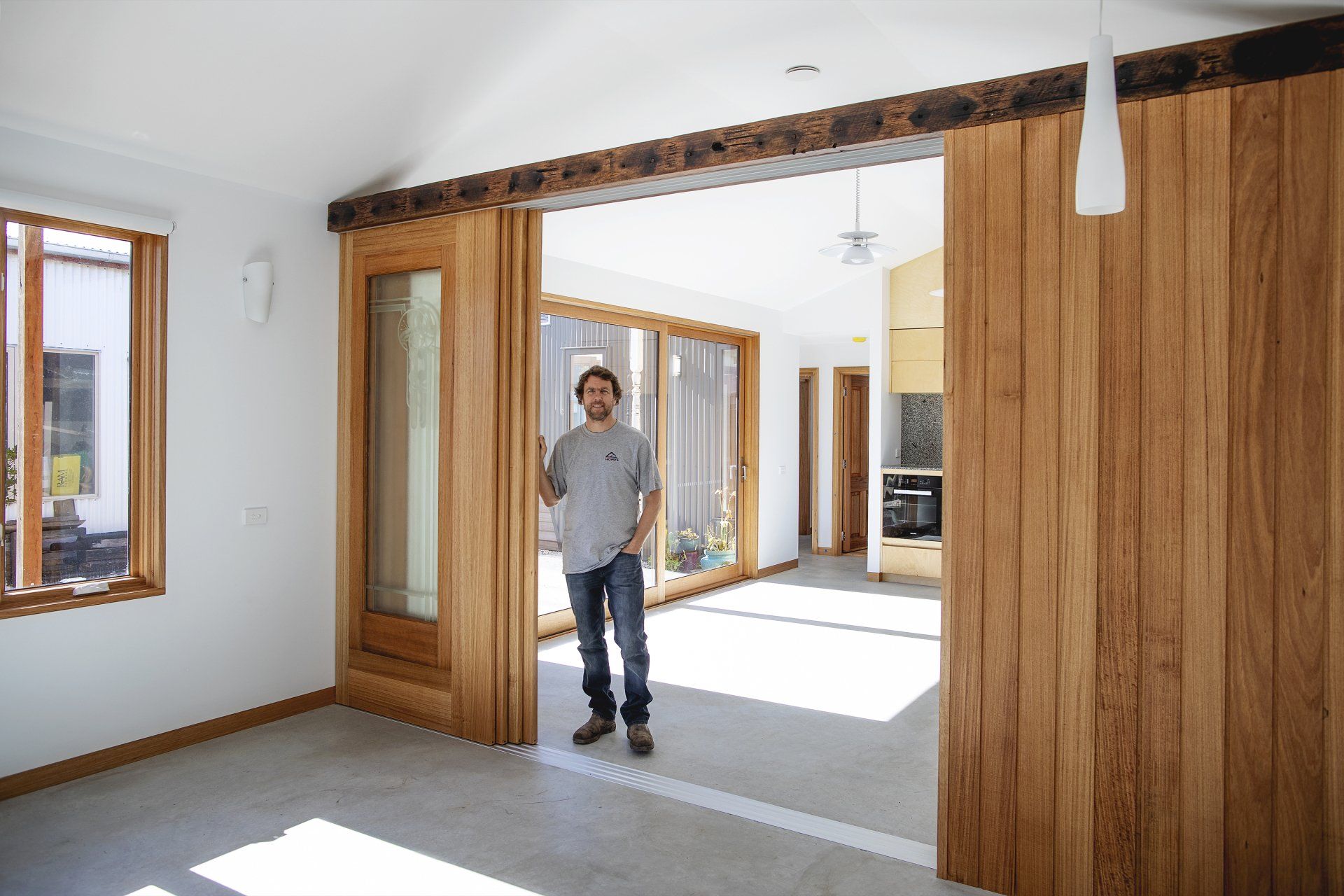 A man is standing in an empty room with a wooden wall.