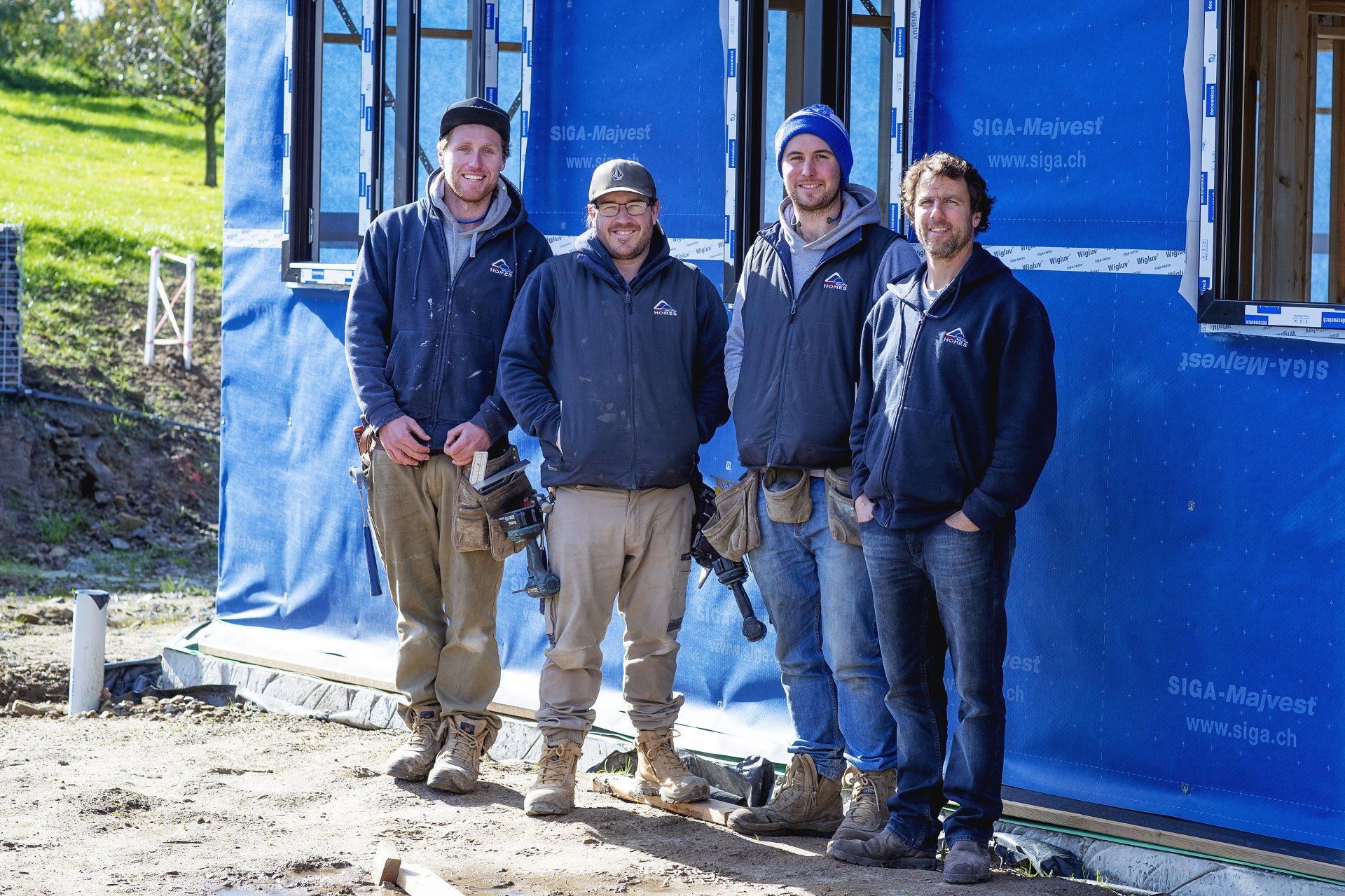 A group of construction workers are posing for a picture in front of a building.