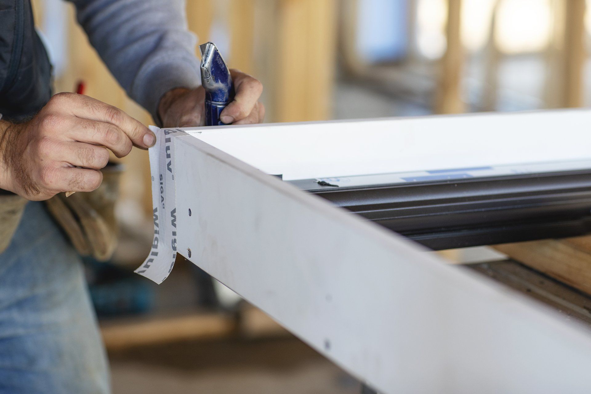 A man is measuring a piece of wood with a tape measure.