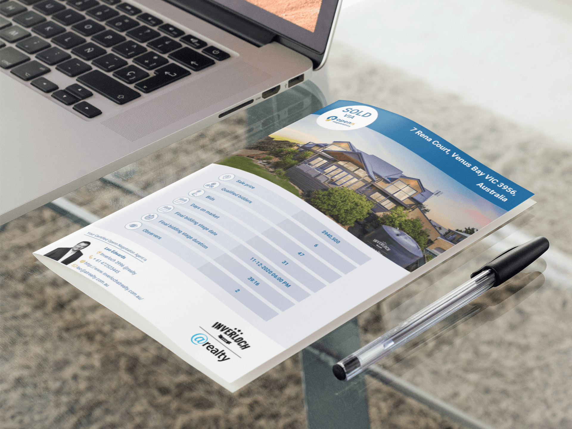 A piece of paper is sitting on a table next to a laptop and a pen.