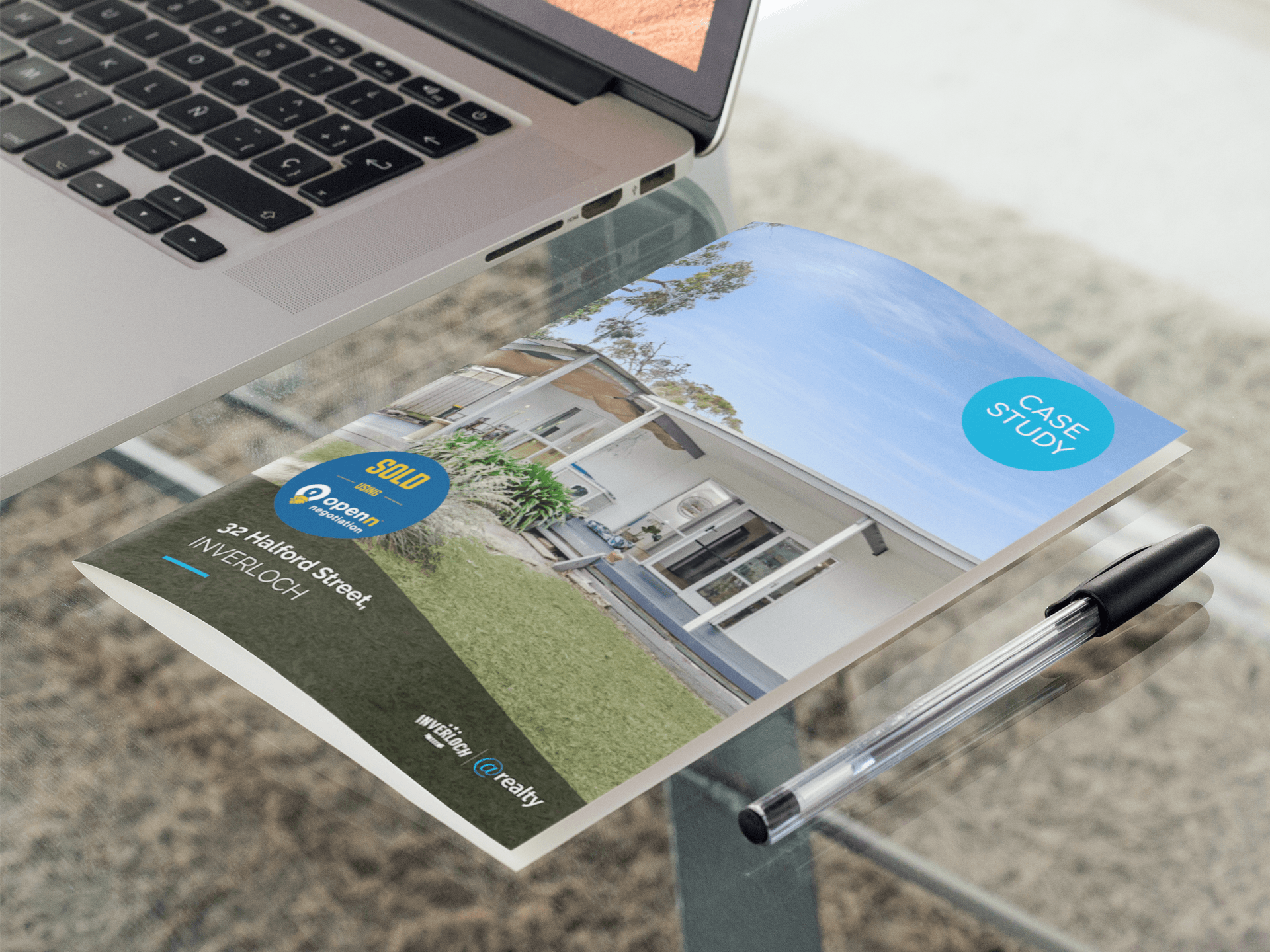 A pen is sitting on a piece of paper next to a laptop.