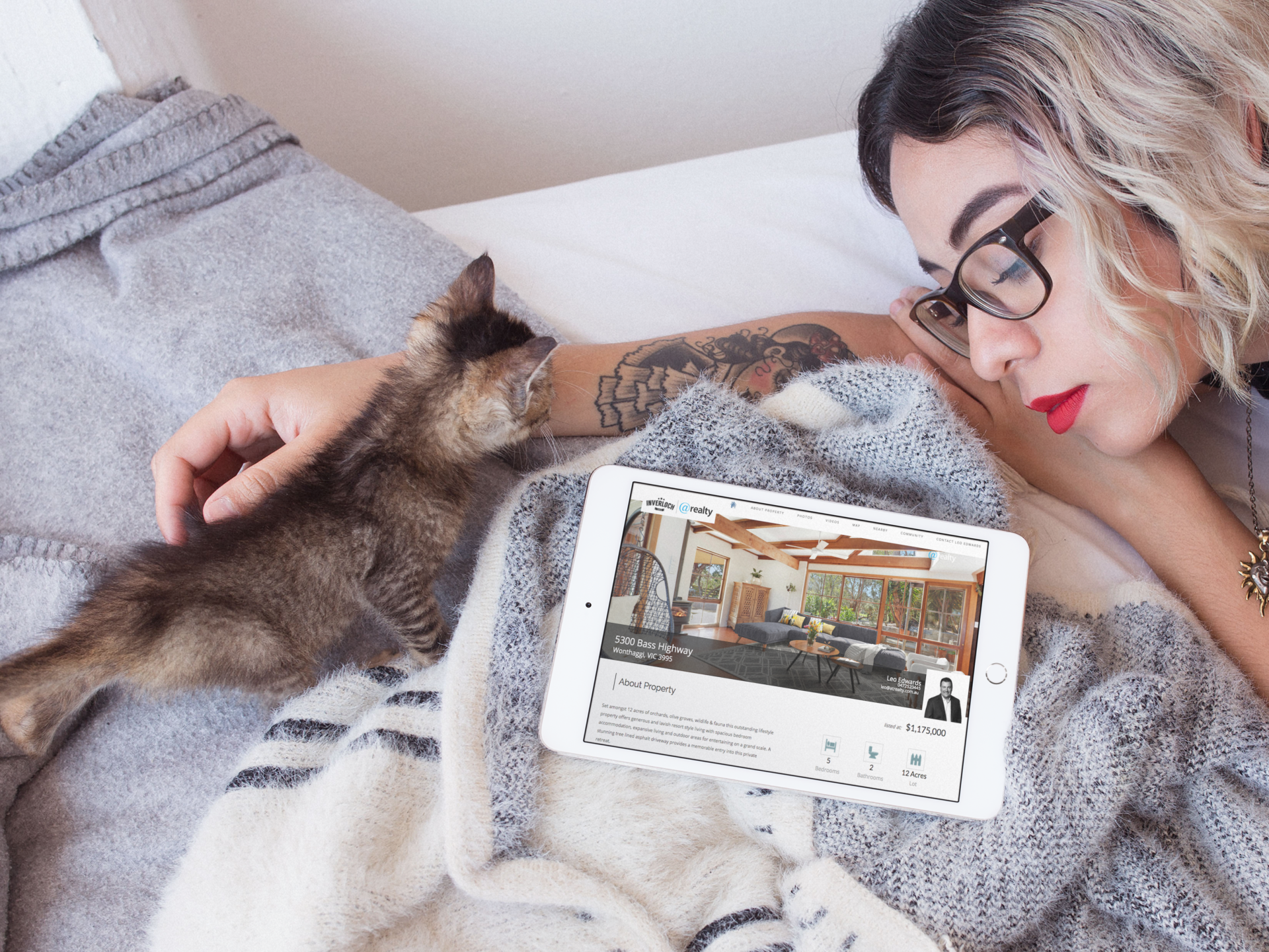 A woman laying on a bed with a cat and a tablet