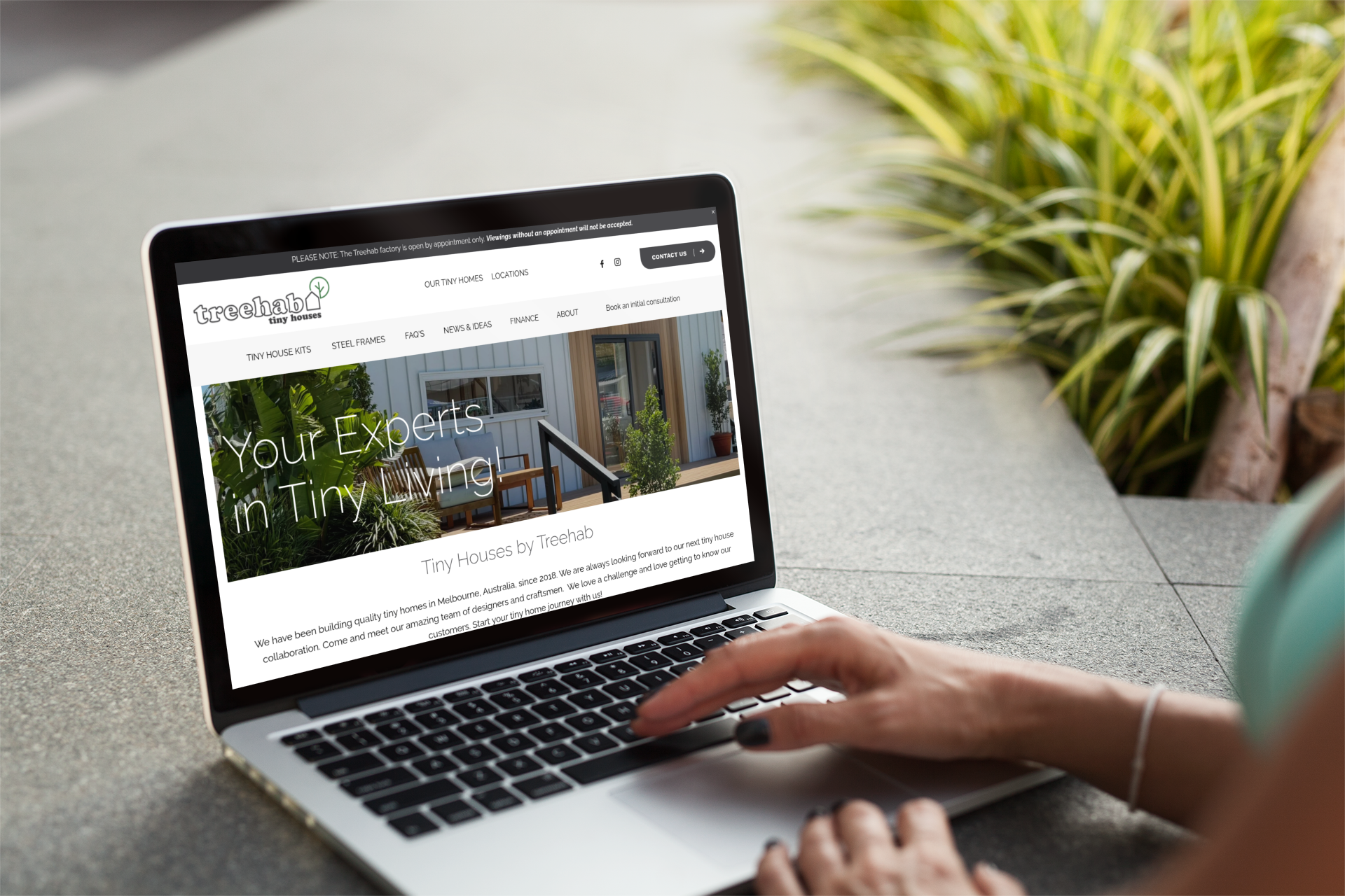 Person using a laptop outdoors with the website 