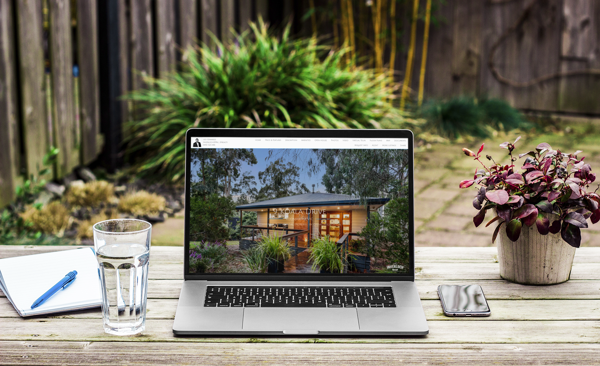 A laptop computer is sitting on a wooden table with a picture of a house on the screen.