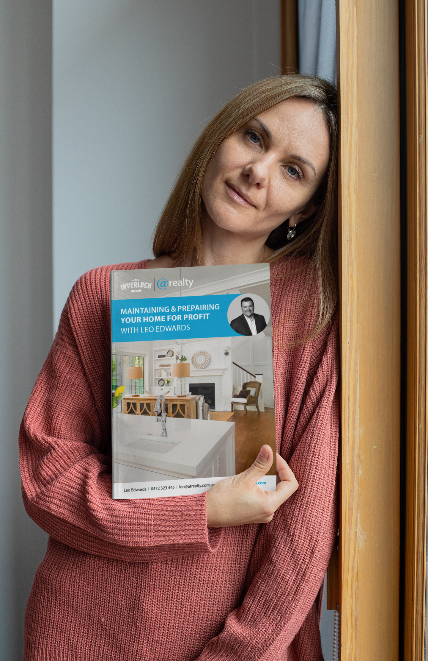 A woman in a pink sweater is holding a book in her hands.