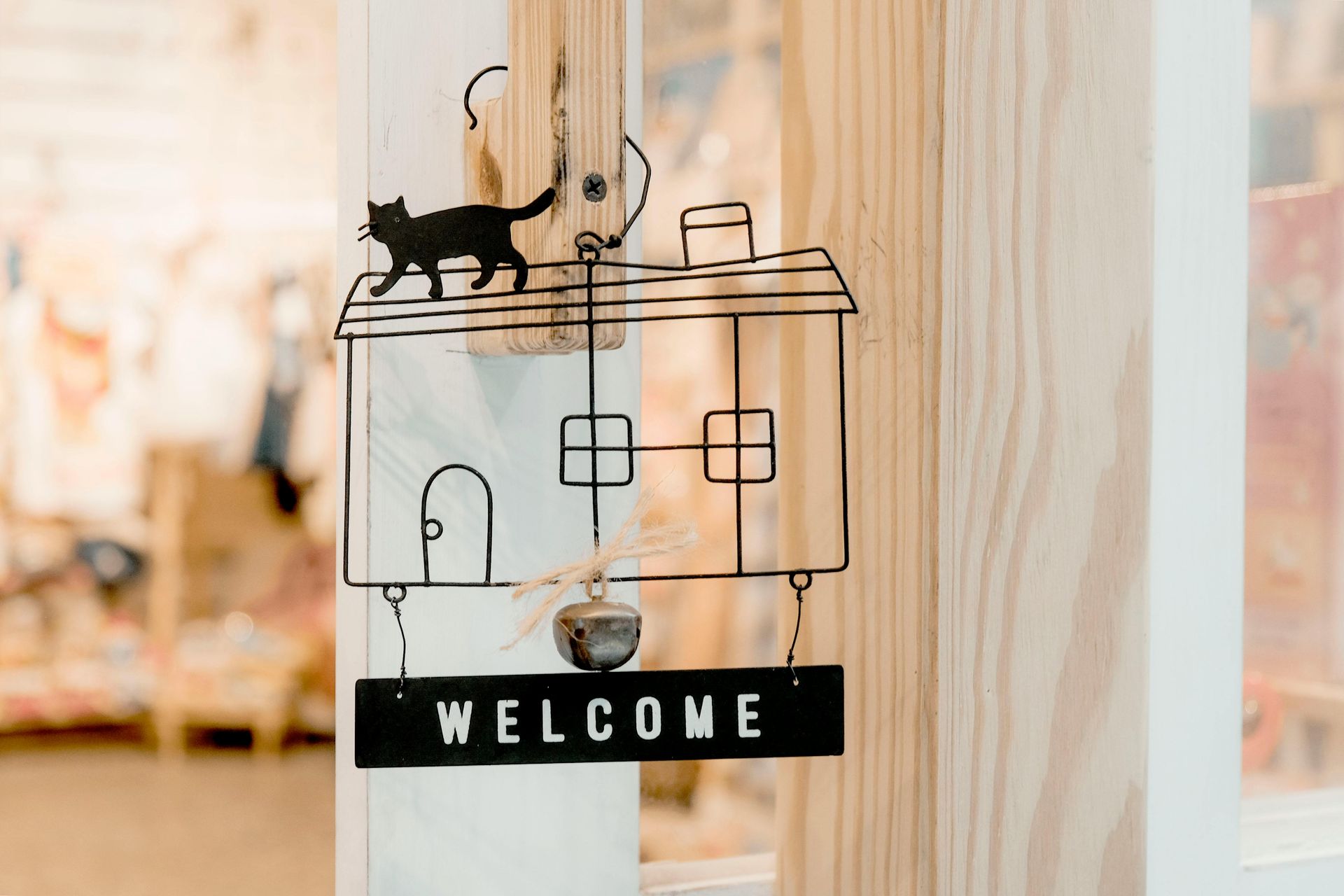 A welcome sign with a cat on top of a house