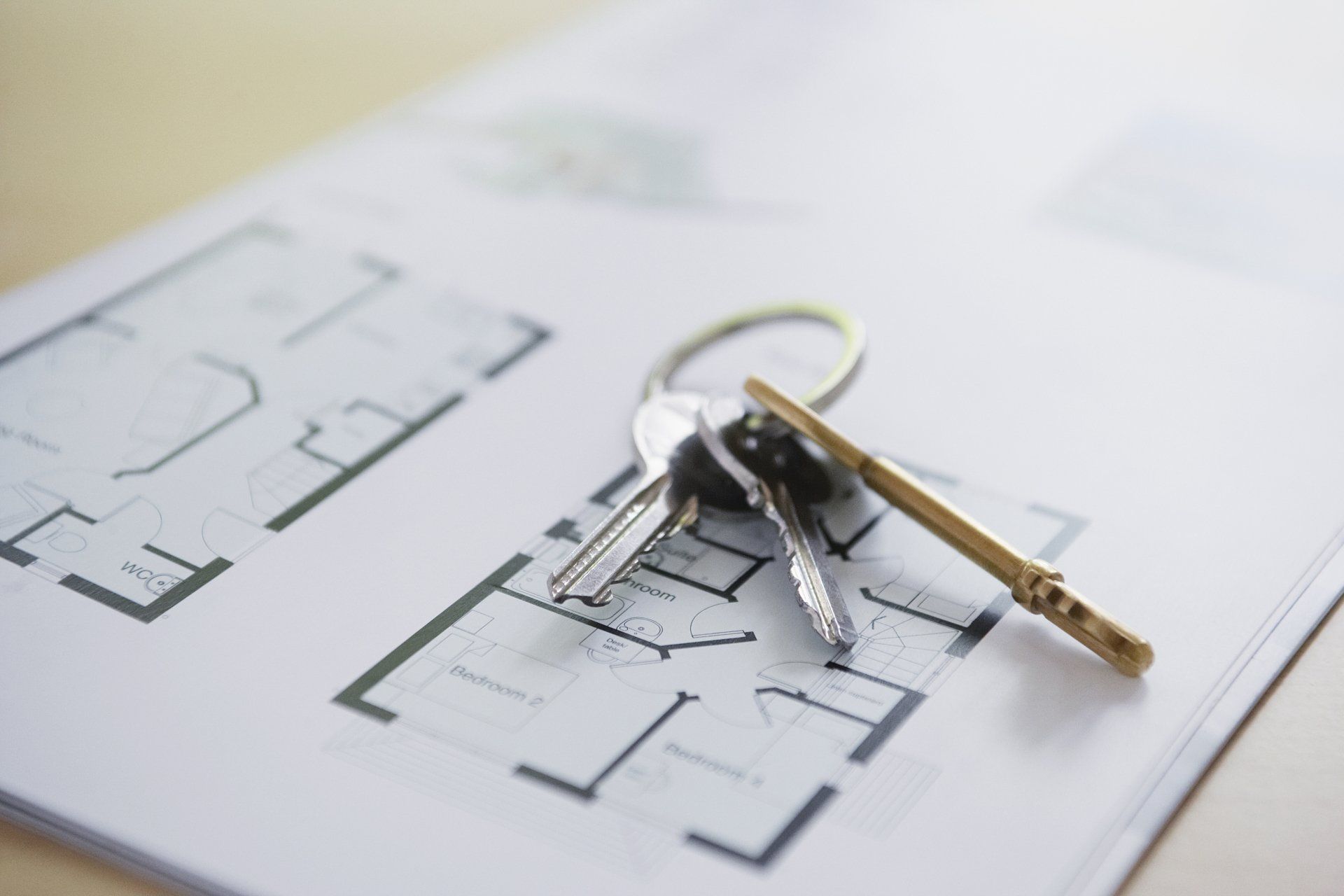 A bunch of keys are sitting on top of a house plan.