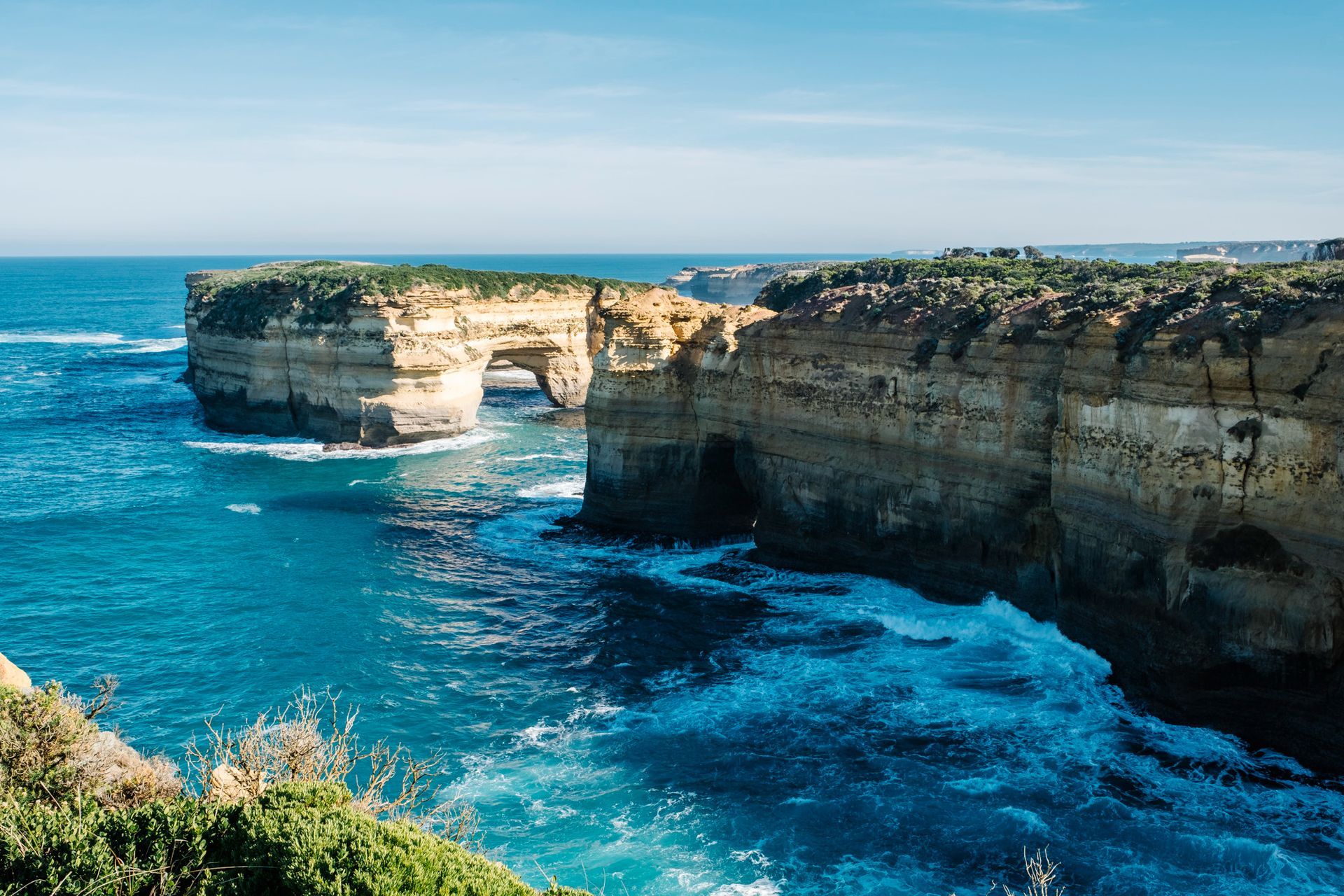 A view of a cliff overlooking the ocean with waves crashing against it.