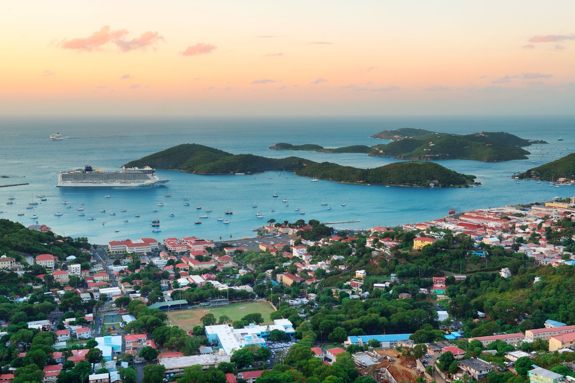 An aerial view of a city with a cruise ship in the distance.