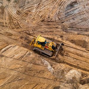 An aerial view of a bulldozer moving dirt on a construction site.