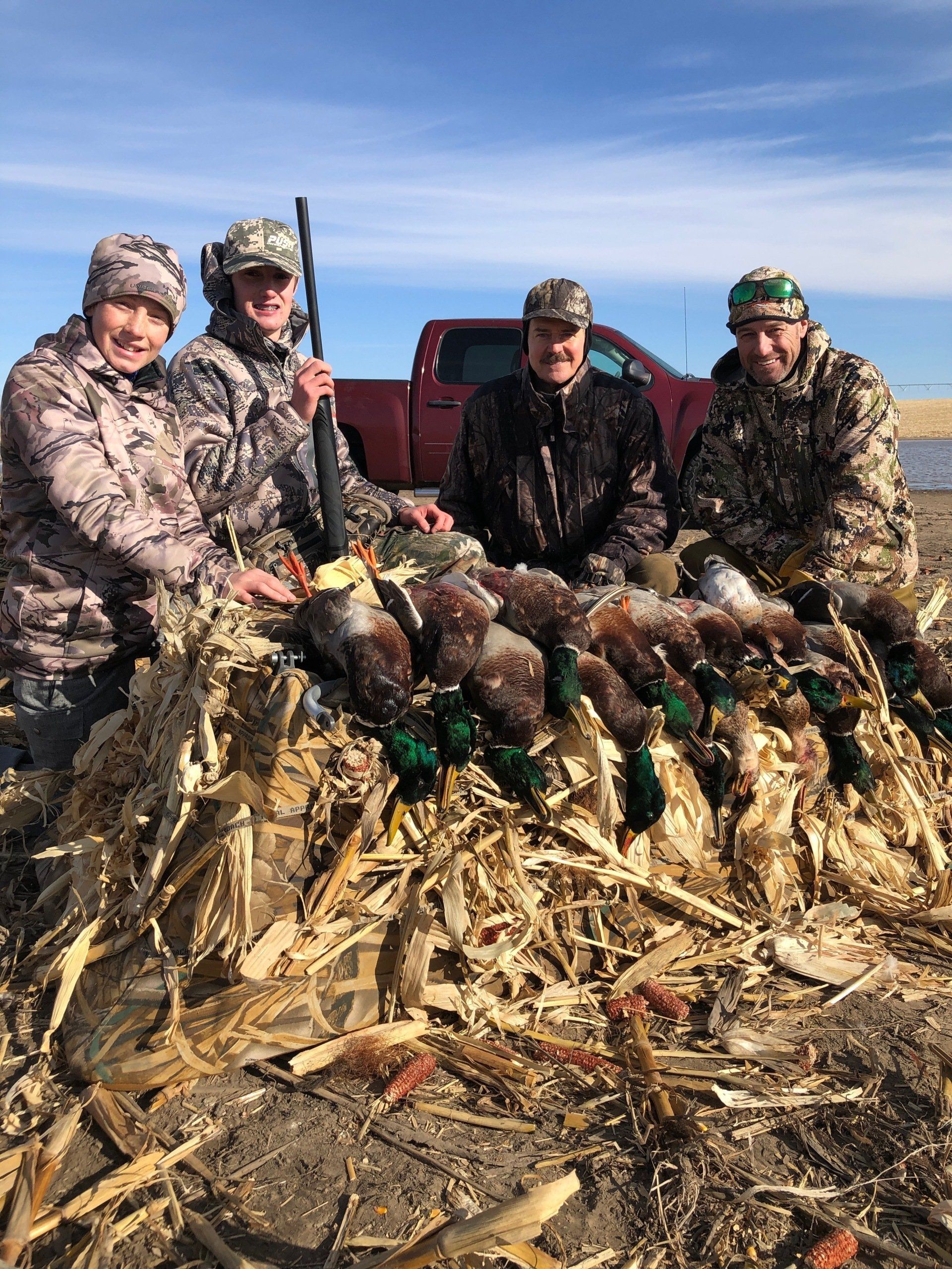A group of people are sitting on top of a pile of corn.