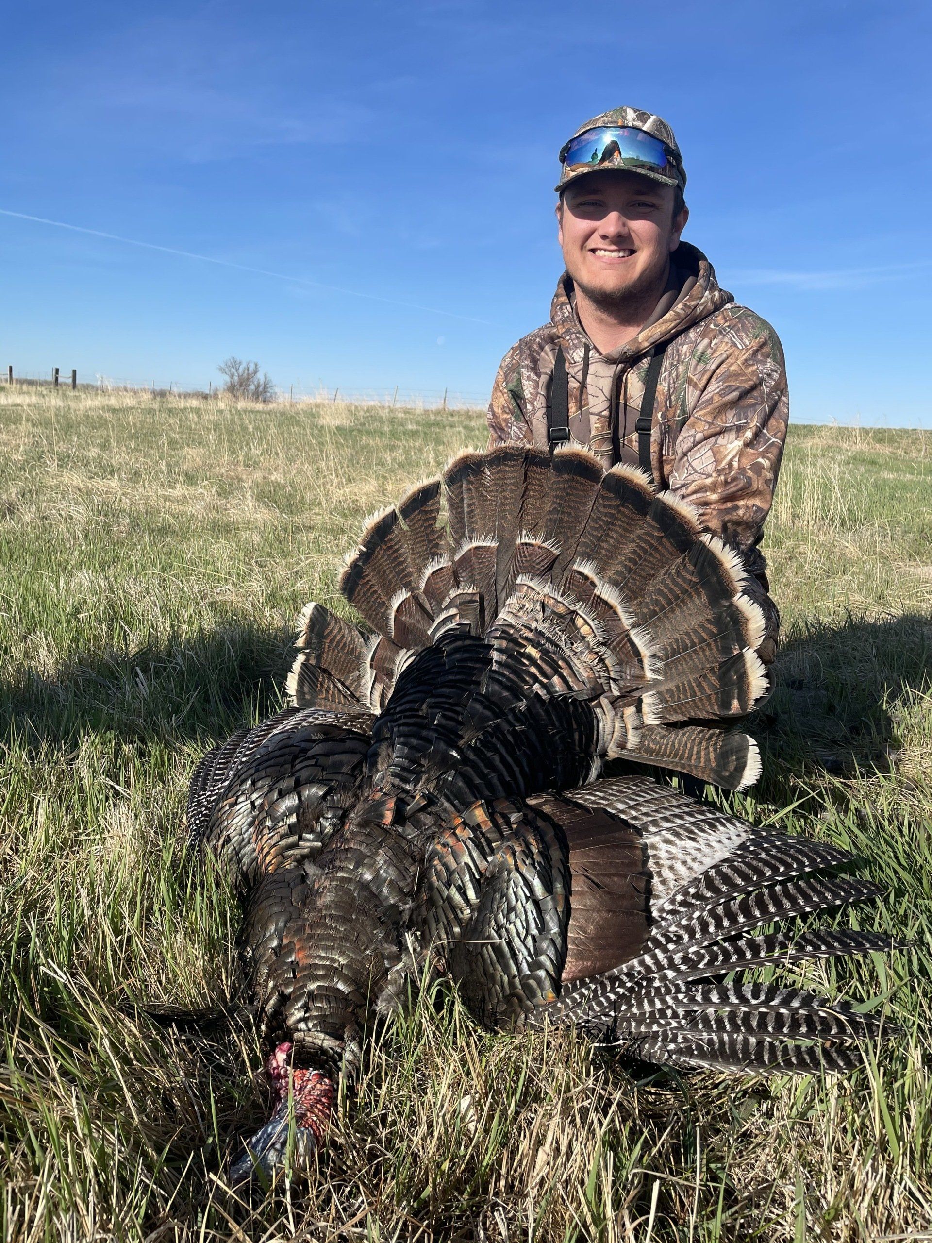 A man is holding a large turkey in a field.