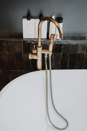 A bathtub with a brass faucet and a shower head attached to it.