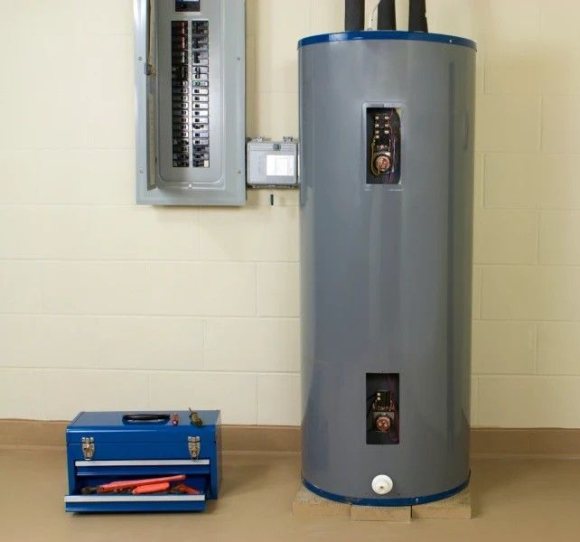 A gray water heater is sitting next to a blue toolbox
