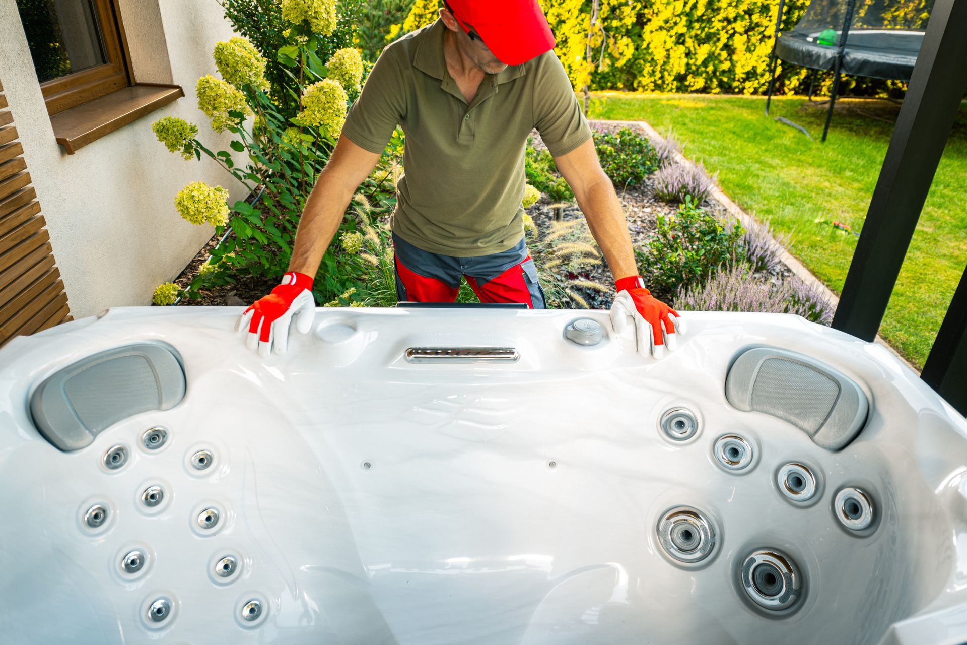 A man in a red shirt and gloves is inspecting a hot tub, showcasing the services of a hot tub supplier. A man in a red shirt and gloves is inspecting a hot tub, showcasing the services of a hot tub supplier.