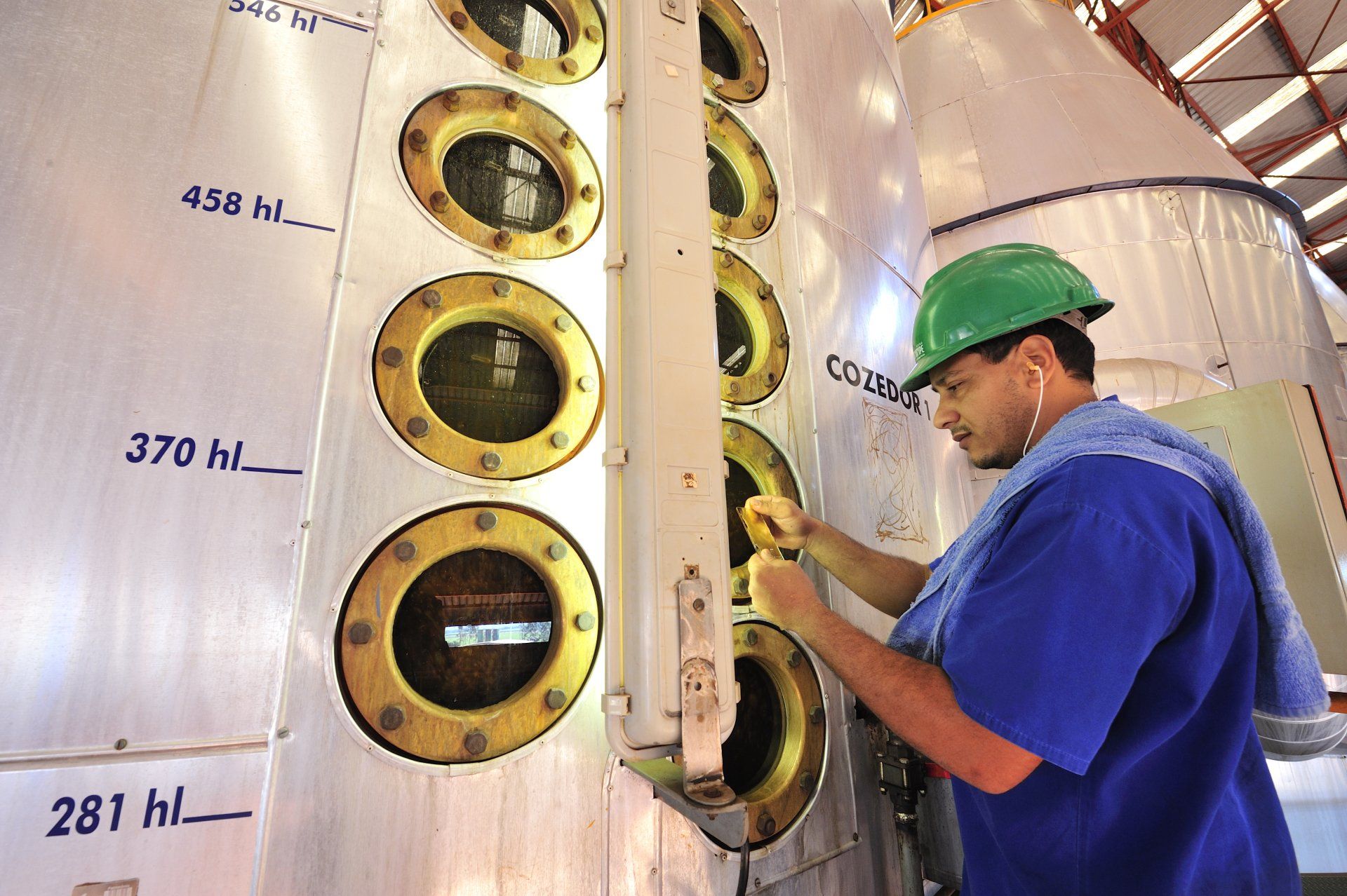 A man wearing a green hard hat is working on a machine