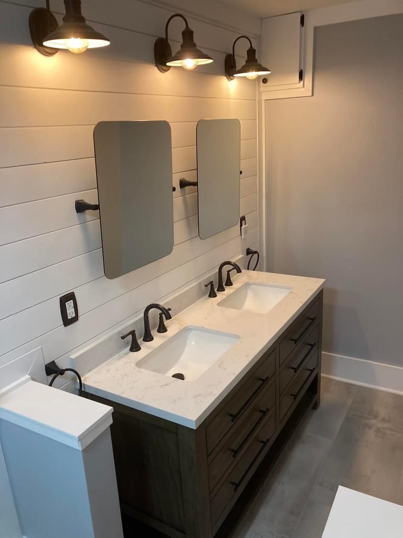 A bathroom with two sinks , two mirrors and a toilet.