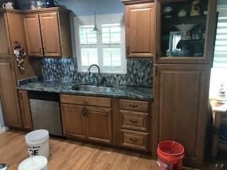 A kitchen with wooden cabinets , granite counter tops , a sink , and a dishwasher.