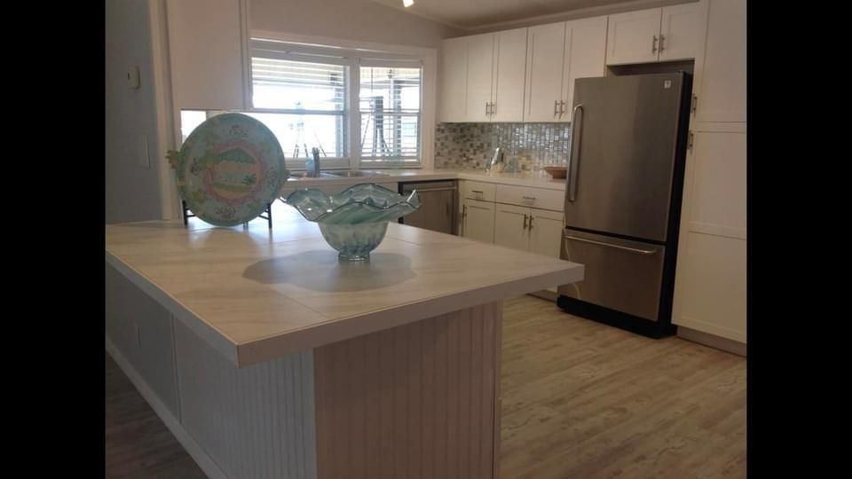 A kitchen with white cabinets and a stainless steel refrigerator.