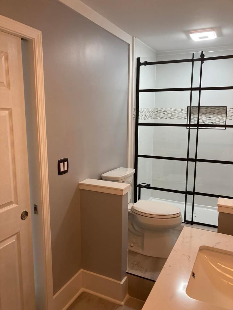 A bathroom with a toilet , sink and shower.