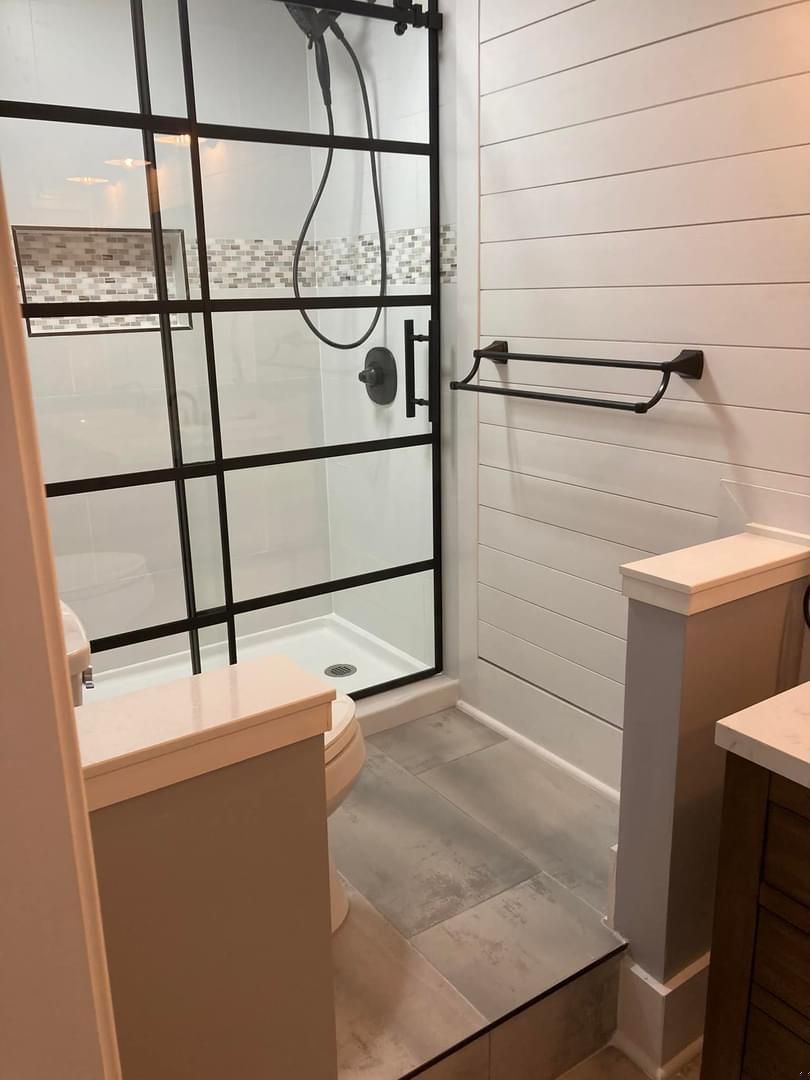 A bathroom with a walk in shower , toilet and sink.