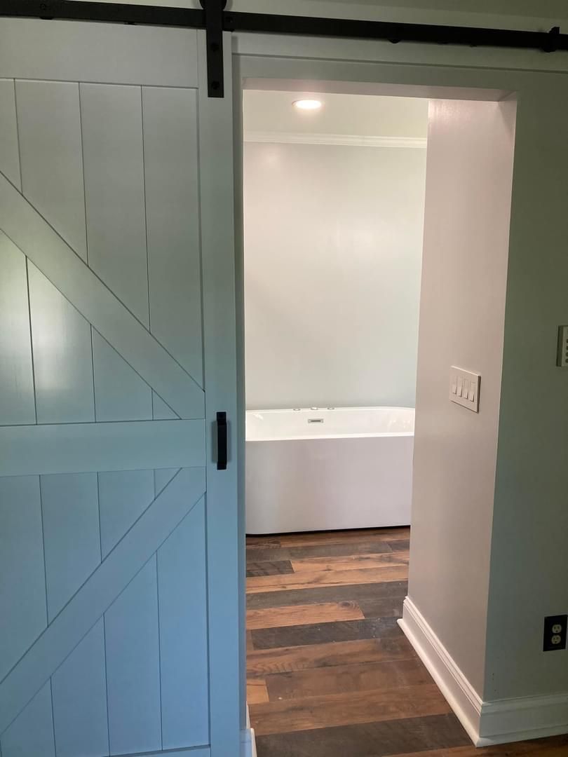 A bathroom with a bathtub and a sliding barn door.