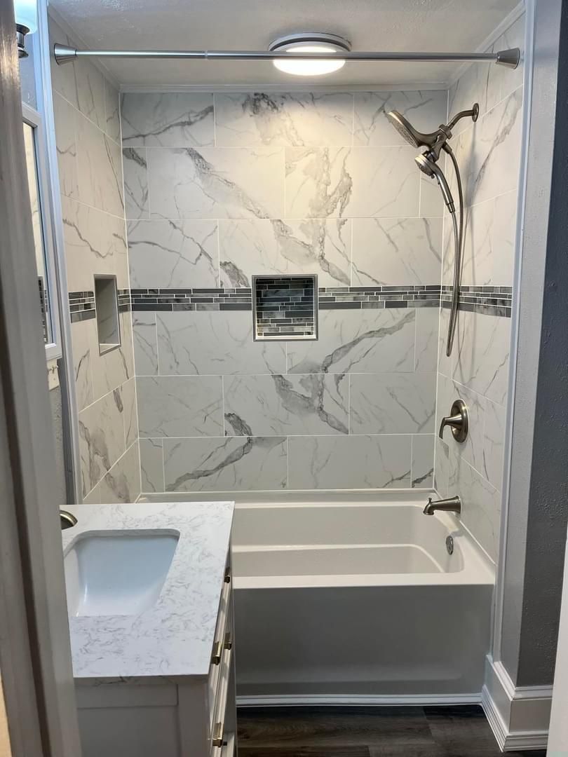 A bathroom with a tub , sink and shower.