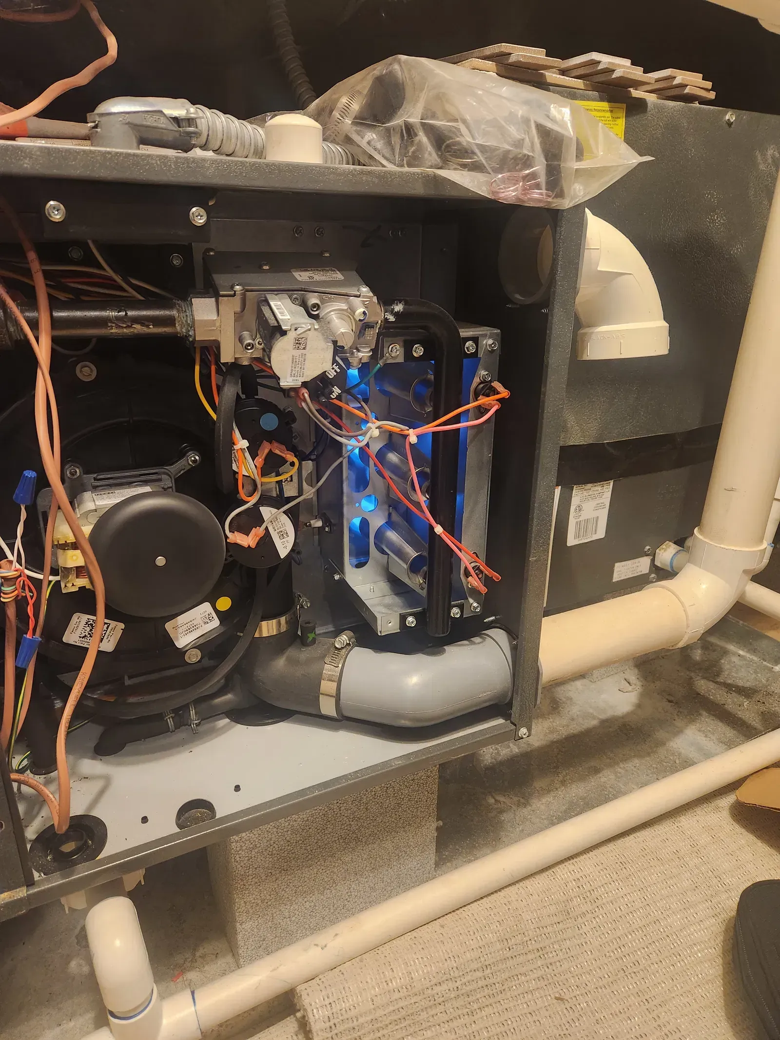 Furnace interior with blue lights, gray duct, and various wires and components.
