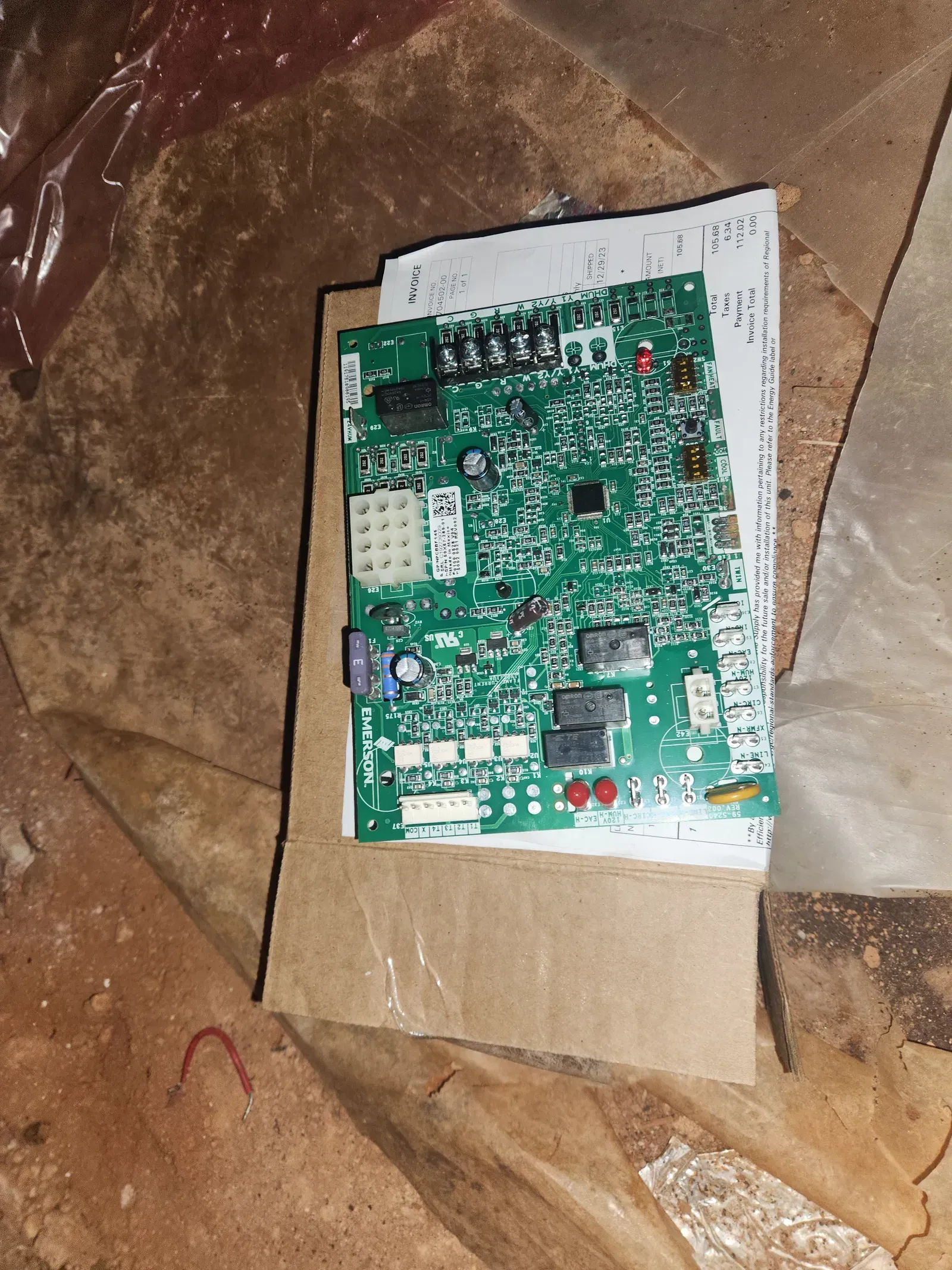 Green circuit board on cardboard, lying on a brown surface.