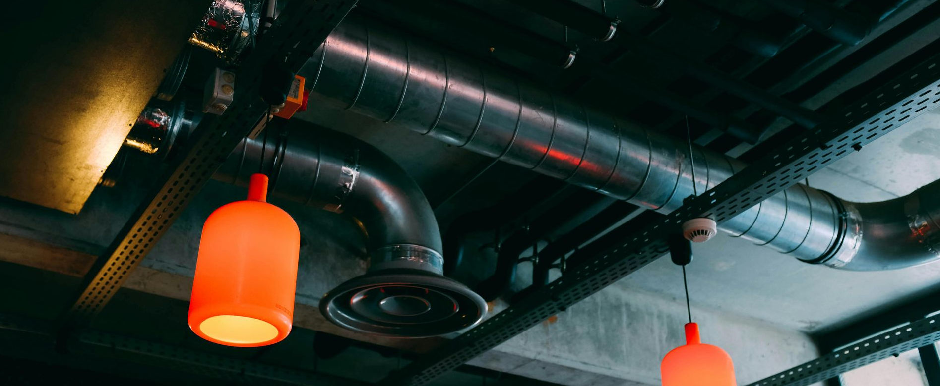 Orange pendant lights hang below exposed metal ductwork.