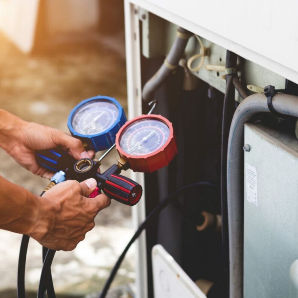 A technician connecting gauges to an air conditioning unit.
