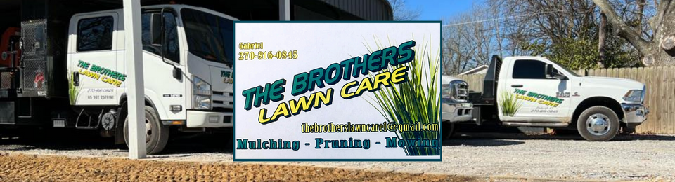 White landscaping trucks with &ldquo;The Mowing Lawn Care&rdquo; logo parked by a dirt road, with grass in the foreground