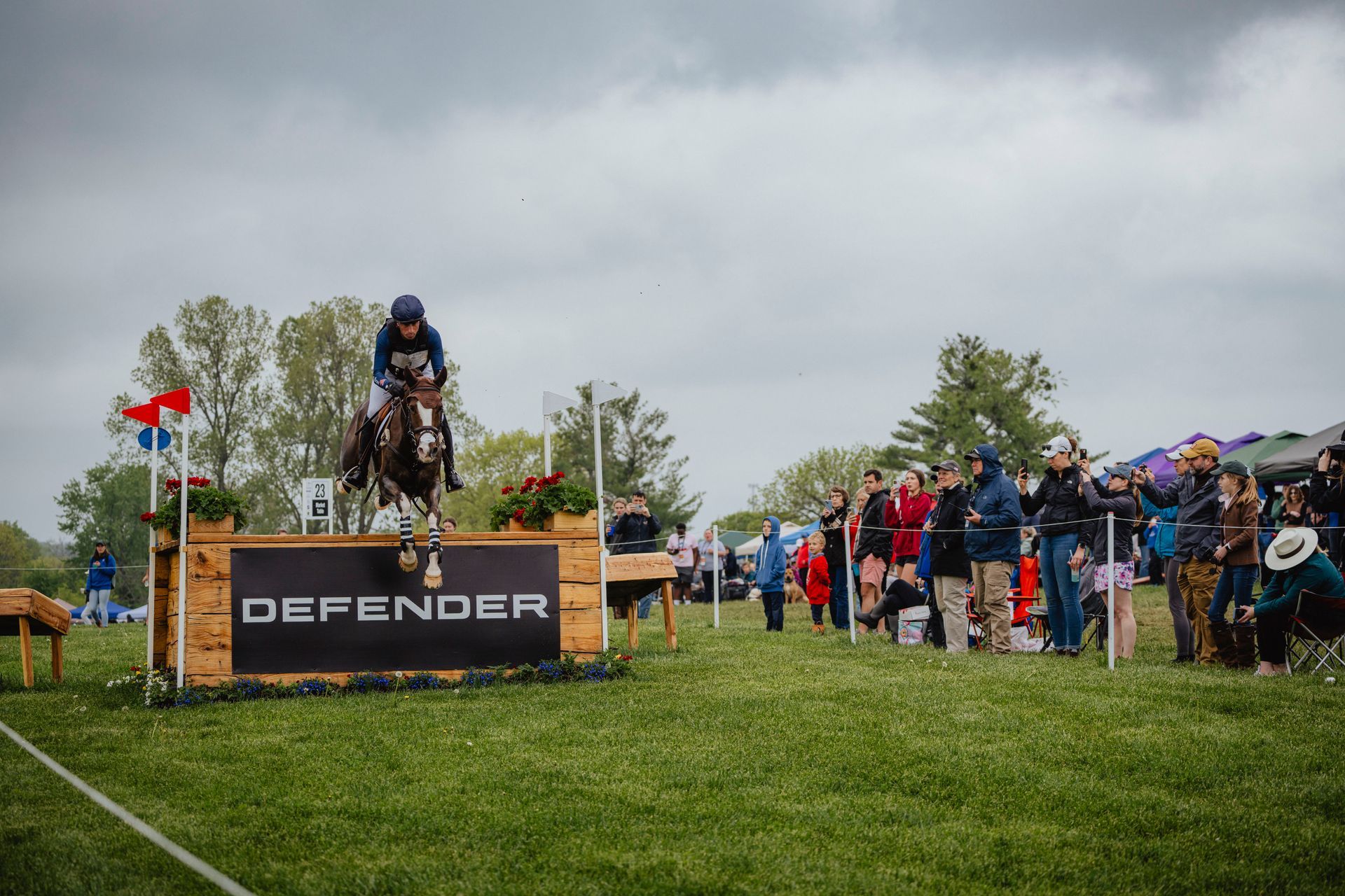 A man on a horse jumping over a wooden fence