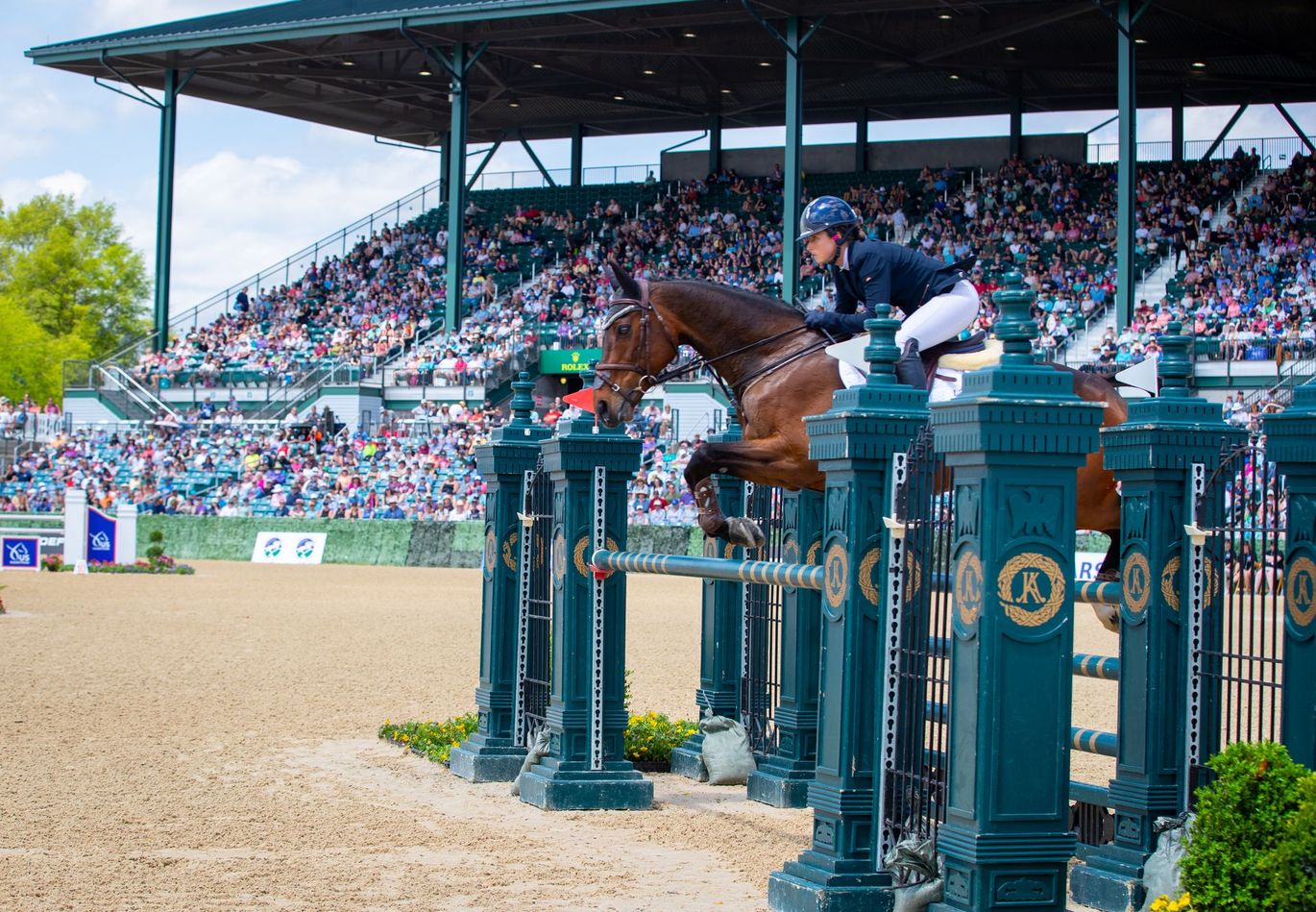 A person is riding a horse over a fence at a horse show.