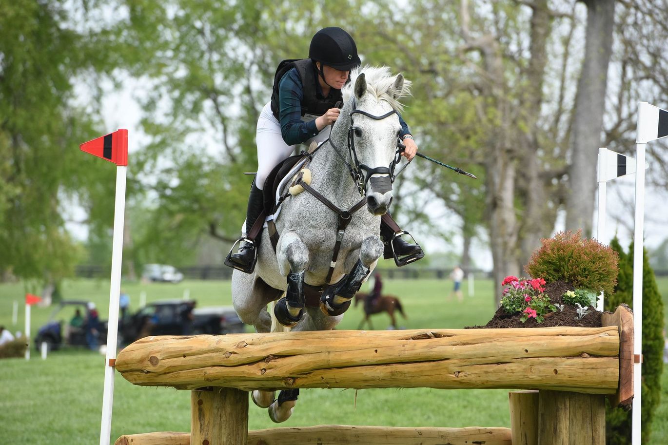 A person is riding a horse over a wooden fence.