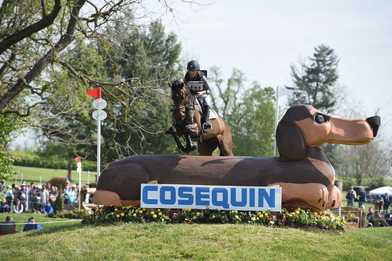 A person is riding a horse on top of an inflatable dachshund.