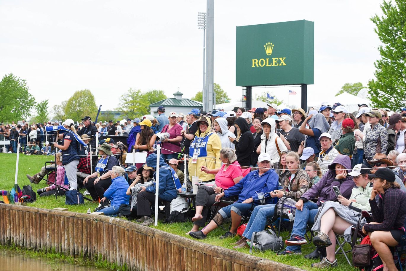 A large group of people are sitting in front of a rolex sign.