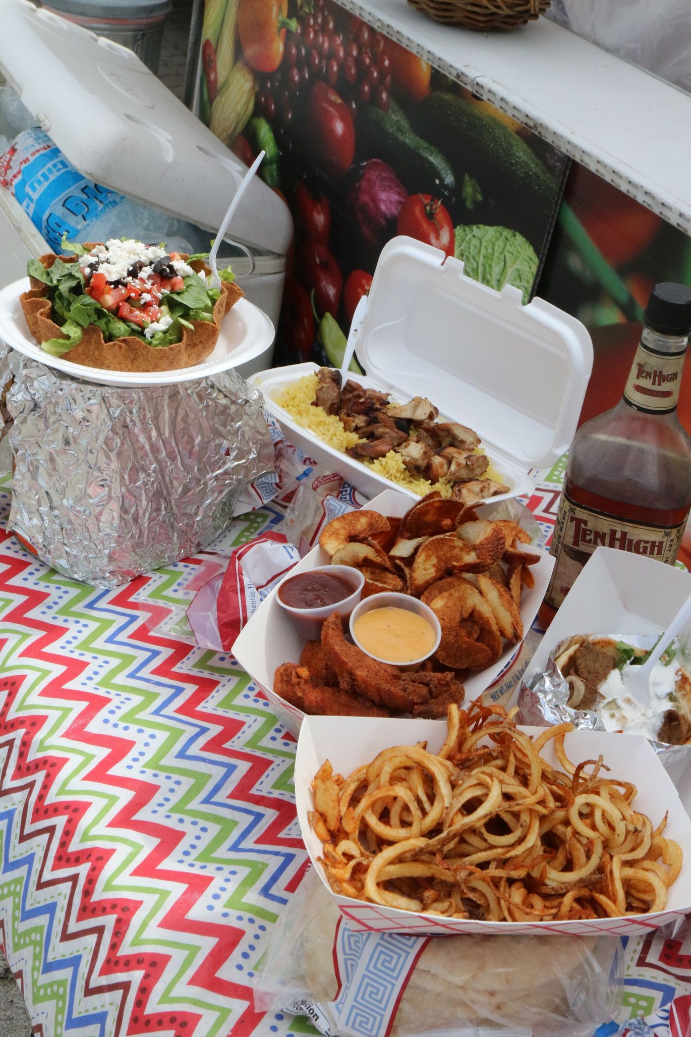 A table topped with plates of food and a bottle of bourbon