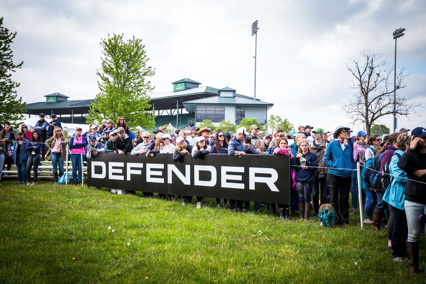 A large group of people are standing in front of a sign that says defender.