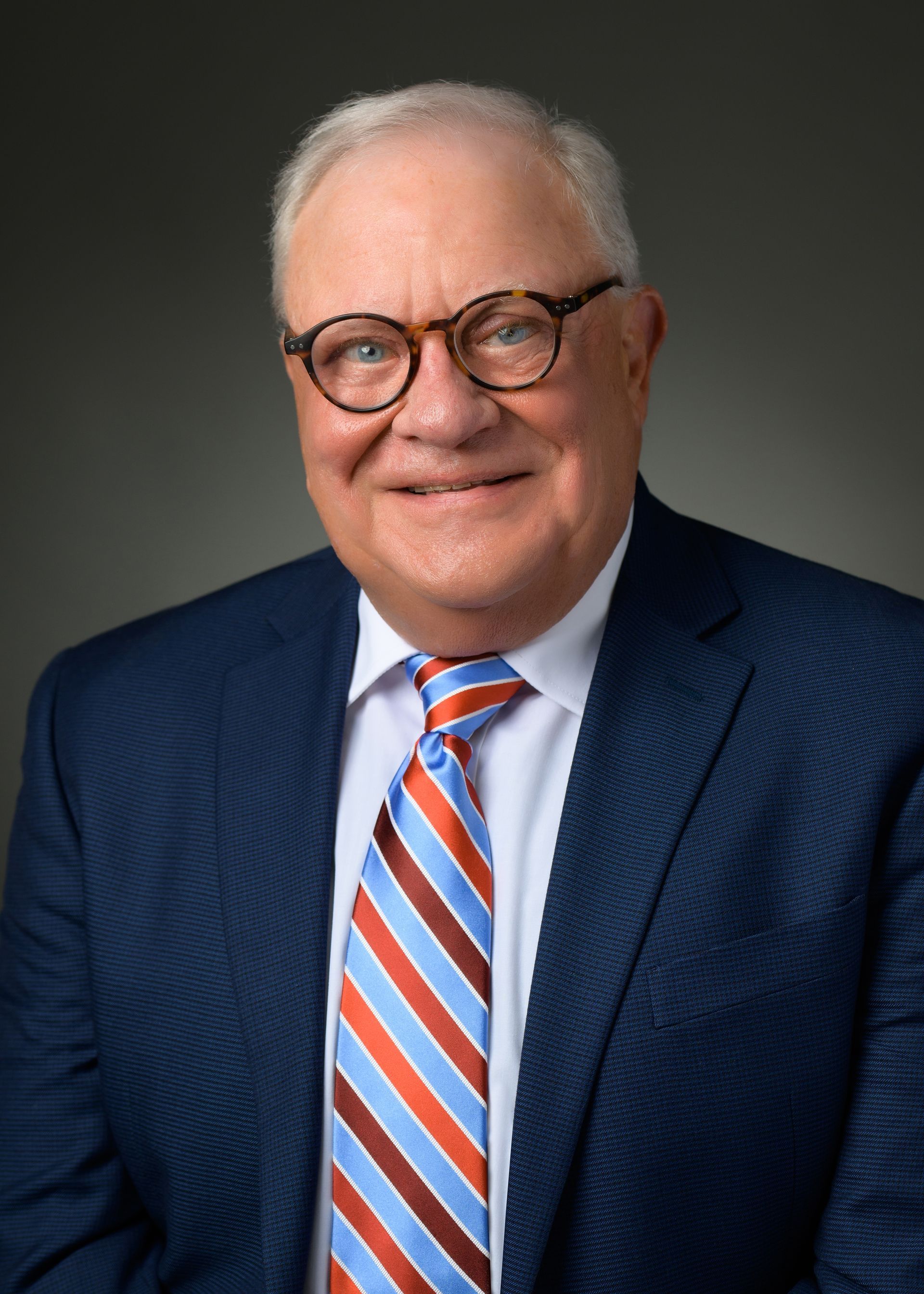 A man in a suit and tie is smiling for the camera.